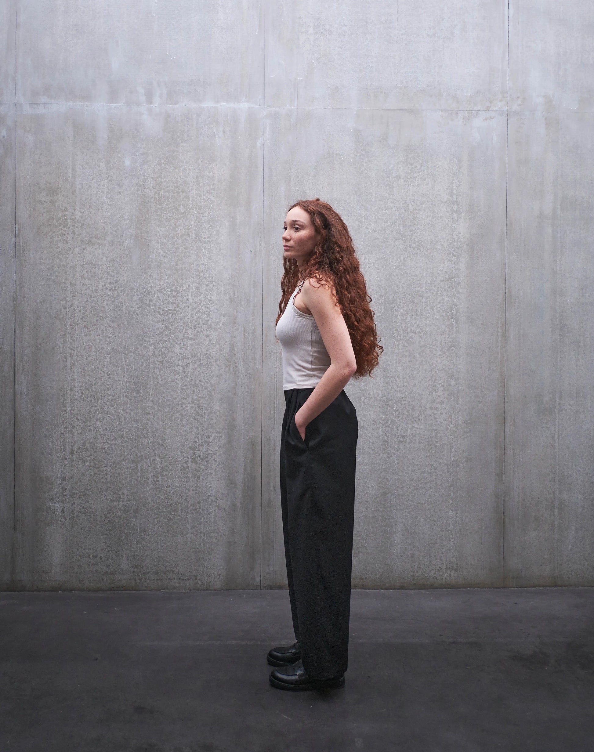Pantalon droit Aïdama, coupe oversize en laine froide noire. Porté par une mannequin femme et vu de profil.