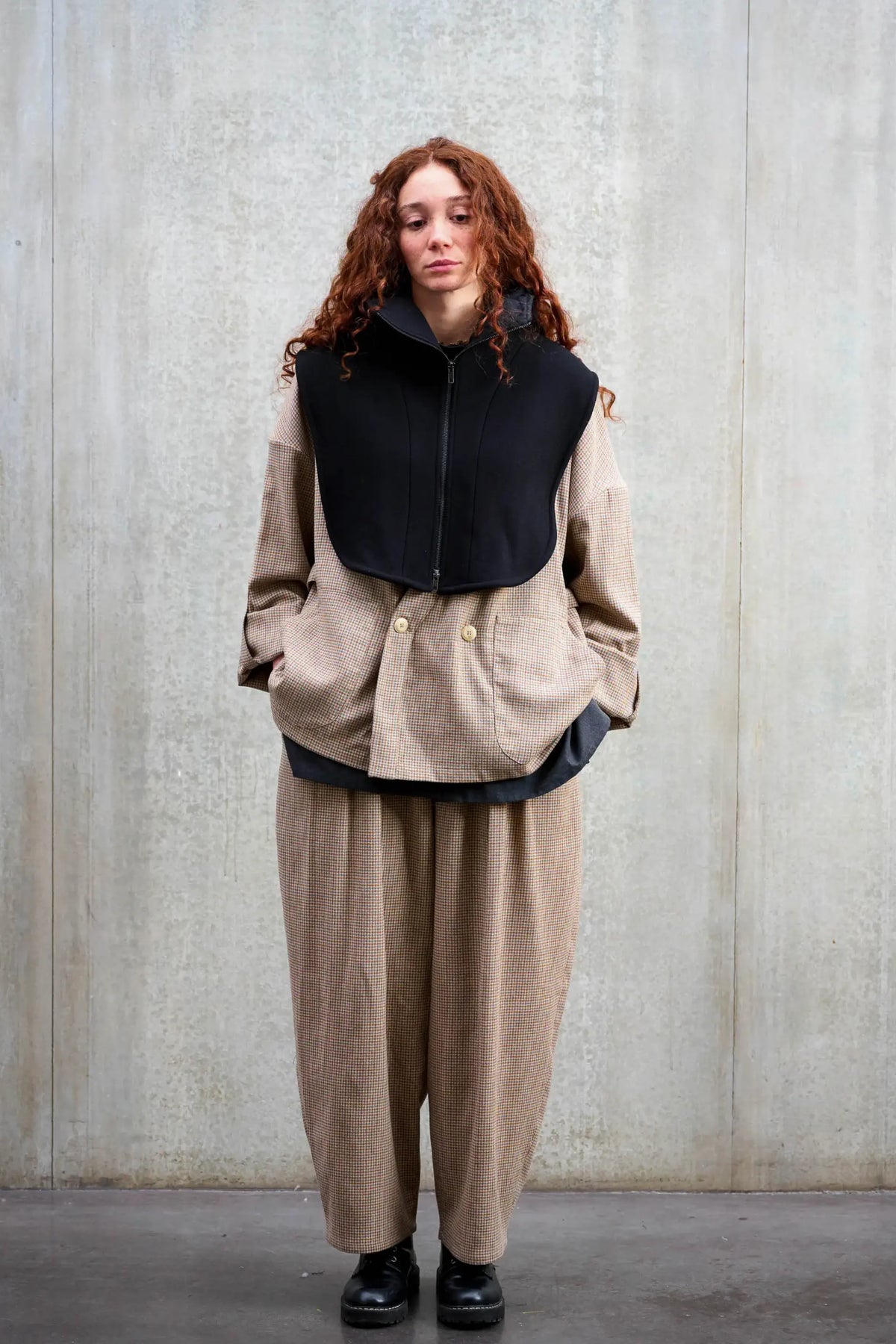 Plastron à capuche de la marque Aïdama, modèle Do en sergé de laine noir. Porté fermé par une mannequin femme et vu de face.