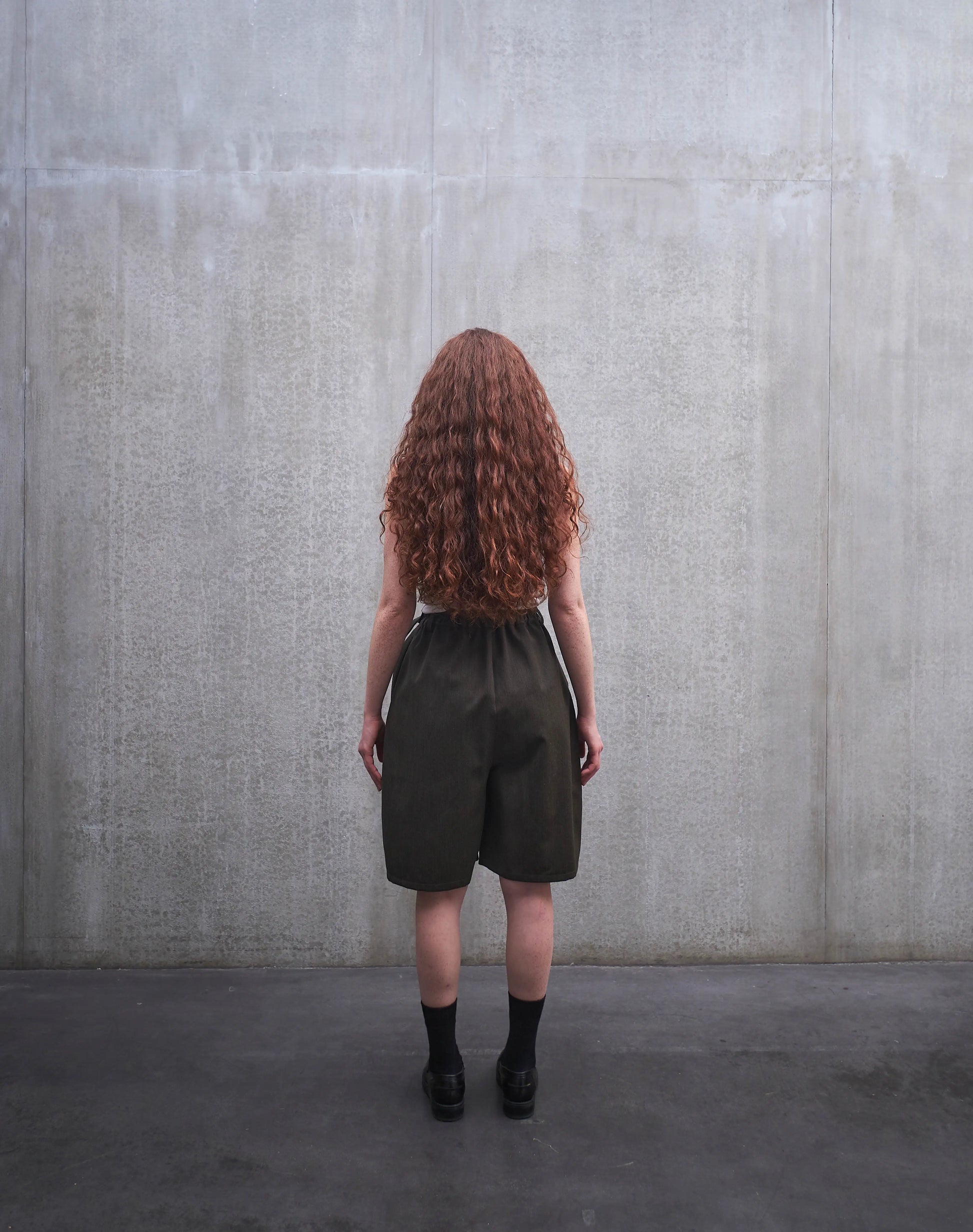 Short oversize Aïdama, coupe ballon en laine froide vert chiné. Porté par une mannequin femme et vu de dos.