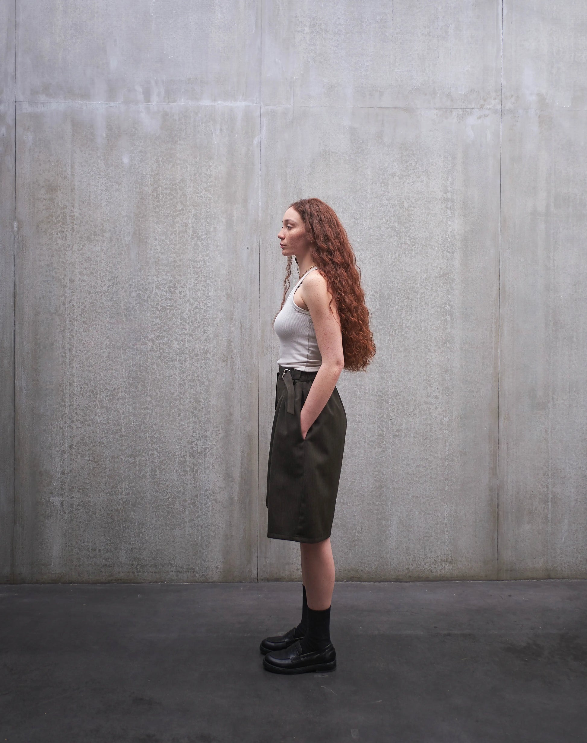 Short oversize Aïdama, coupe ballon en laine froide vert chiné. Porté par une mannequin femme et vu de profil.
