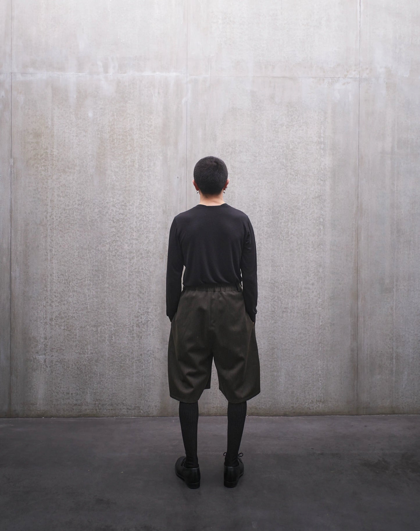 Short oversize Aïdama, coupe ballon en laine froide vert chiné. Porté par un mannequin homme et vu de dos.