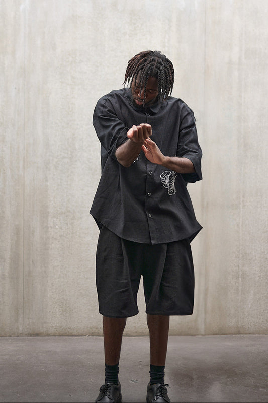 Short Jinbei de la marque Aïdama, coupe ample en laine et lin noir avec sangles ajustables. Porté par un mannequin homme et vu de face.