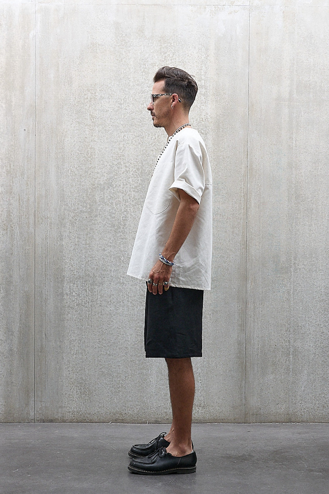 Short Jinbei de la marque Aïdama, coupe ample en laine et lin noir avec sangles ajustables. Porté par un mannequin homme et vu de profil.