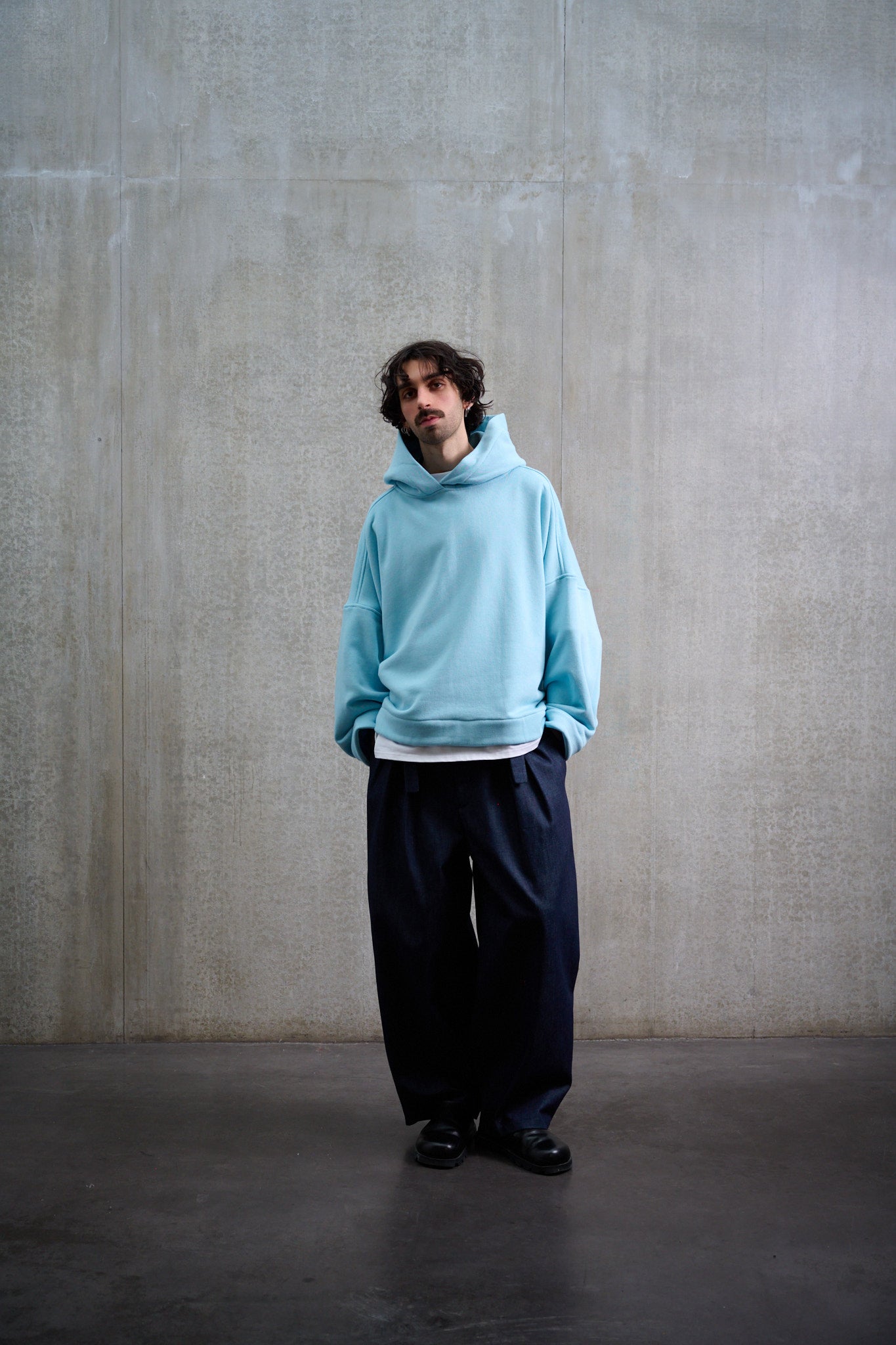 Sweat à capuche oversize en molleton de coton bleu pâle Mino de la marque Aïdama. Porté par un mannequin homme et vu de face.