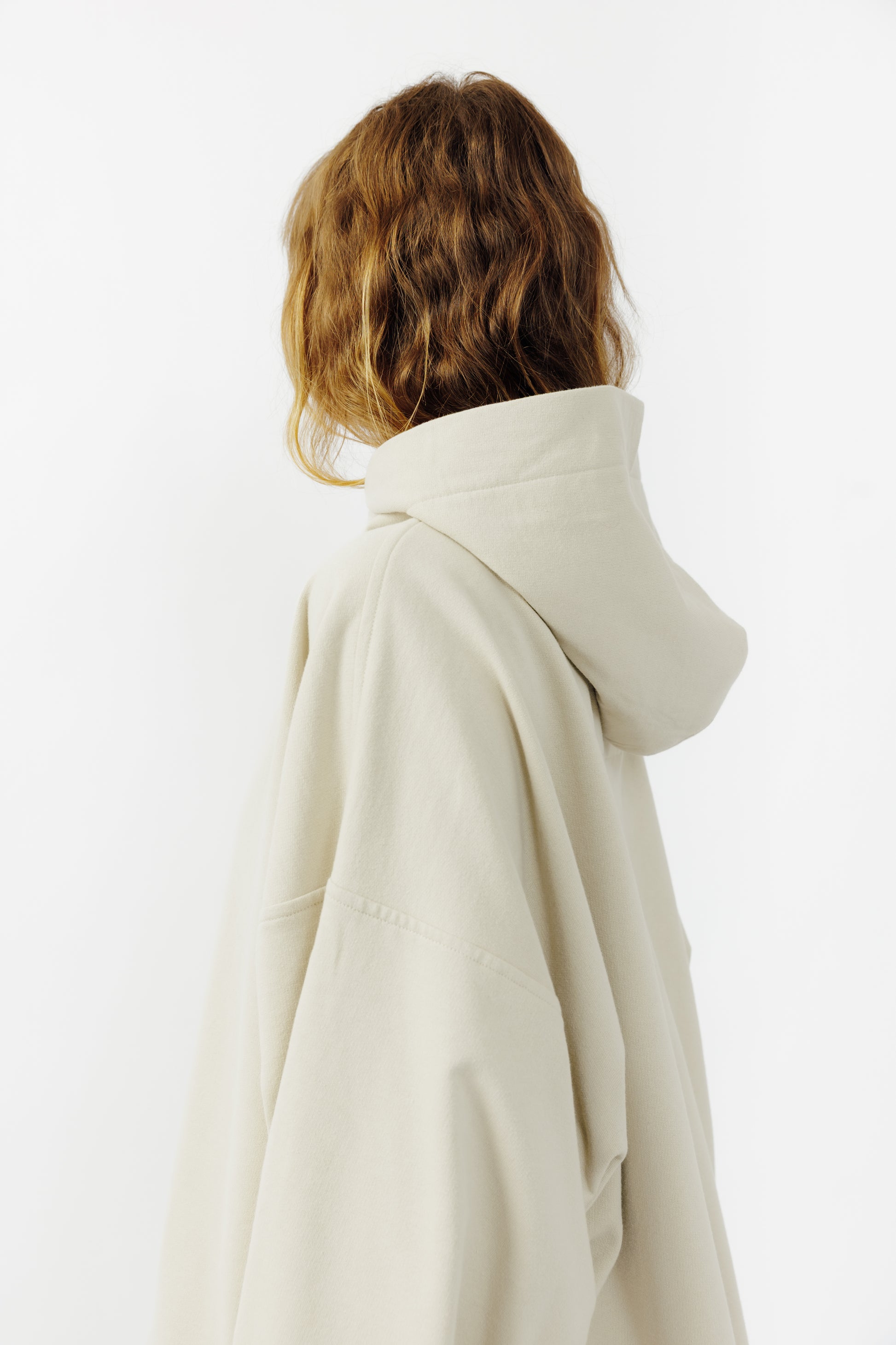 Sweat à capuche oversize Mino de la marque Aïdama en molleton de coton beige. Porté par une mannequin femme et vu de dos. 