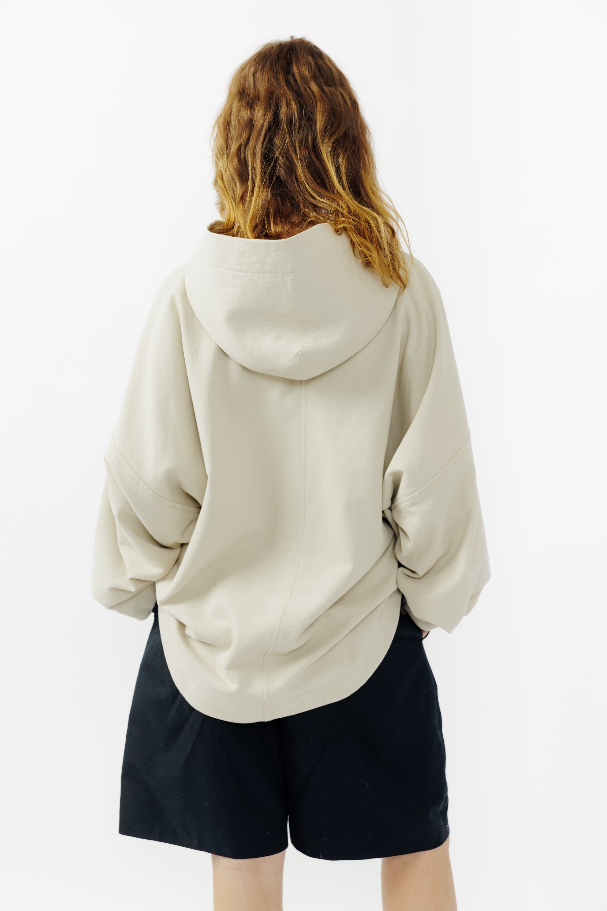 Sweat à capuche oversize Mino de la marque Aïdama en molleton de coton beige. Porté par une mannequin femme et vu de dos.