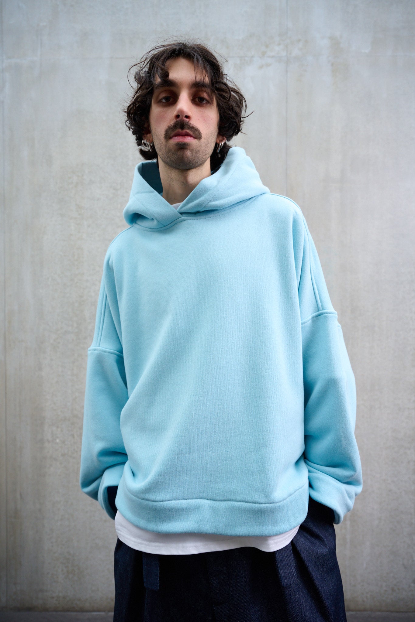 Sweat à capuche oversize en molleton de coton bleu pâle Mino de la marque Aïdama. Porté par un mannequin homme et vu de face.