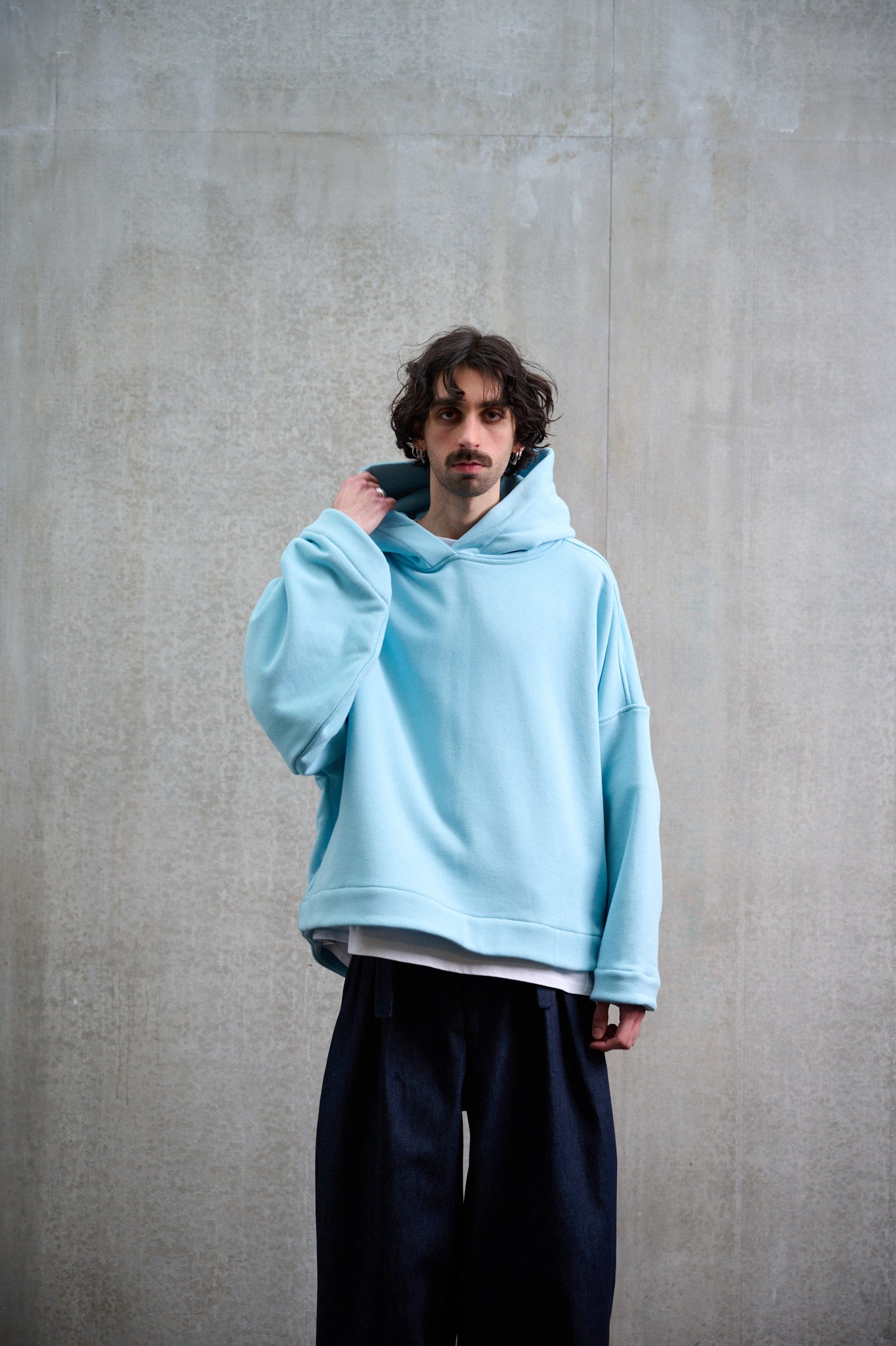 Sweat à capuche oversize en molleton de coton bleu pâle Mino de la marque Aïdama. Porté par un mannequin homme et vu de face.