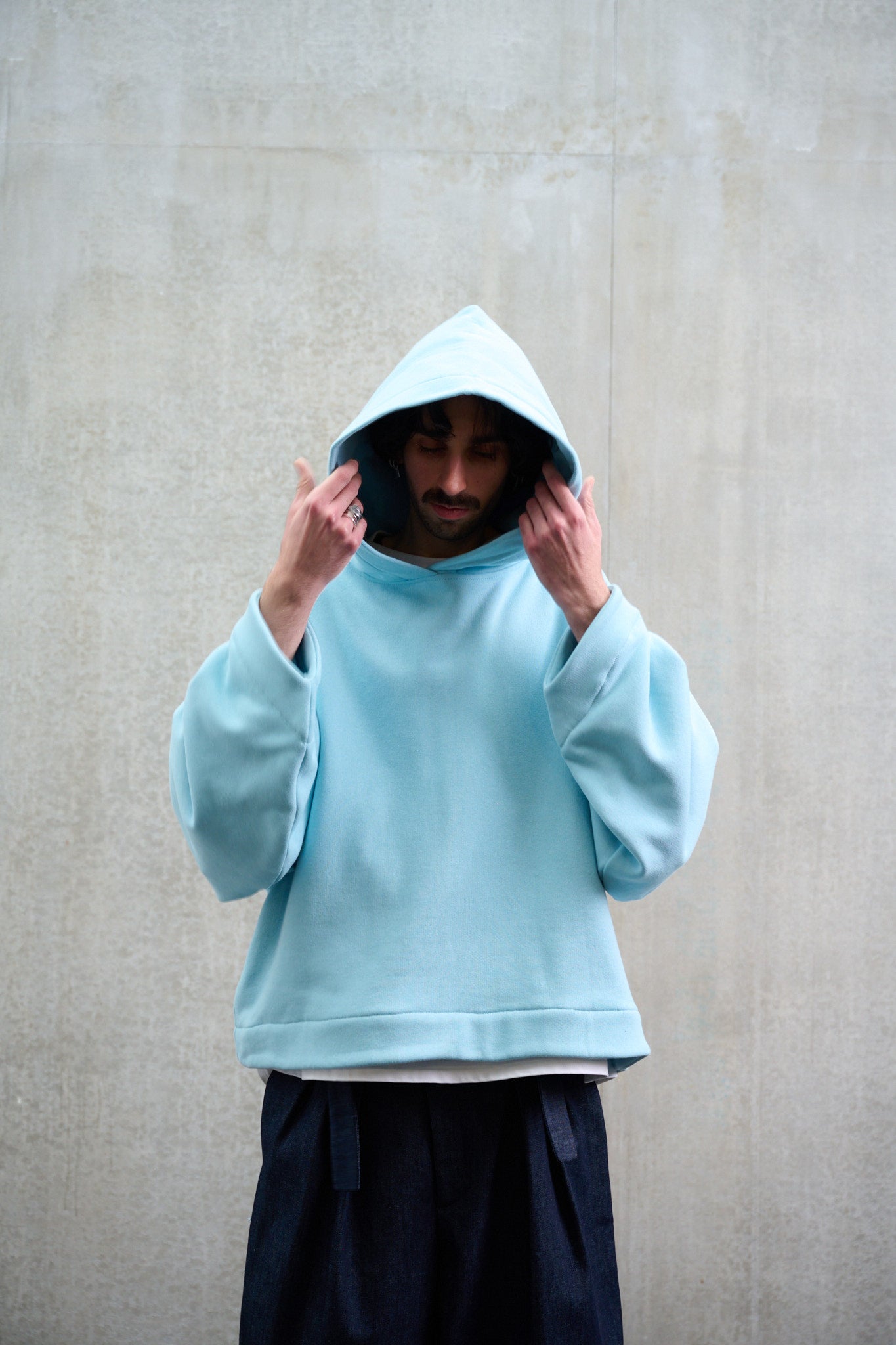 Sweat à capuche oversize en molleton de coton bleu pâle Mino de la marque Aïdama. Porté capuché par un mannequin homme et vu de face.