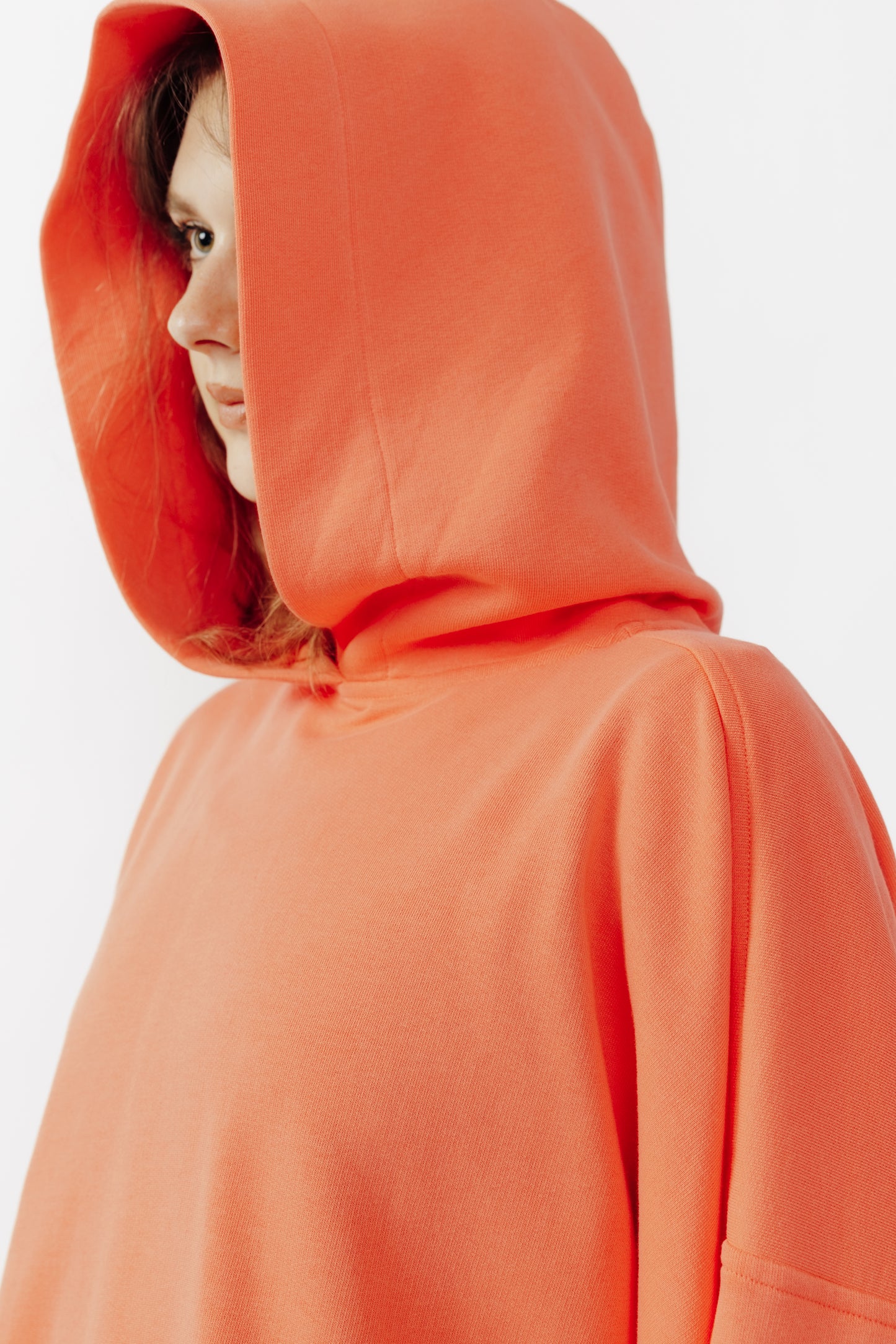 Sweat à capuche oversize Mino de la marque Aïdama en molleton de coton corail. Porté capuche relevée par une mannequin femme et vu zoomé.