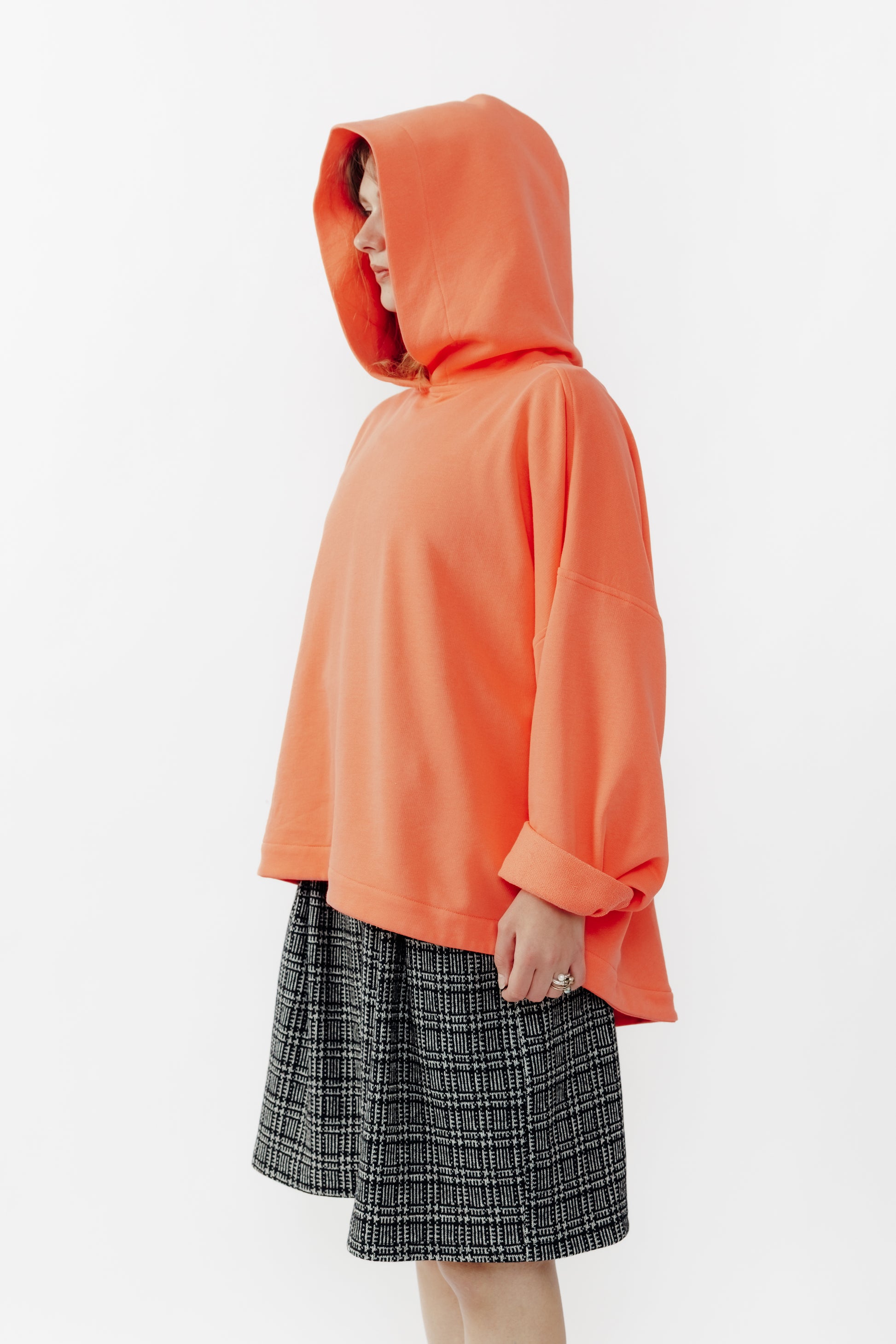 Sweat à capuche oversize Mino de la marque Aïdama en molleton de coton corail. Porté capuche relevée par une mannequin femme et vu de face. 