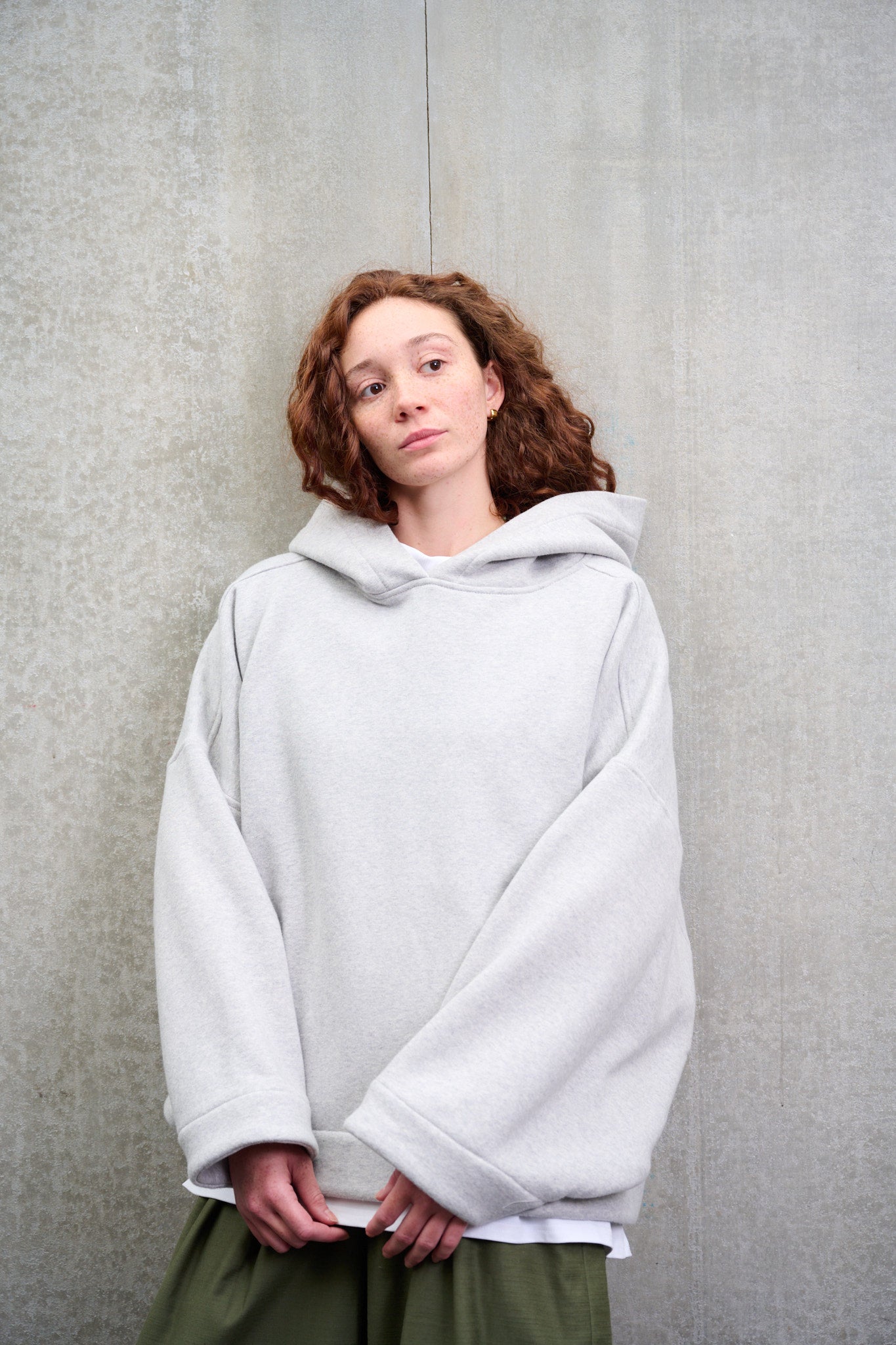 Sweat à capuche oversize en molleton de coton gris chiné Mino de la marque Aïdama. Porté par une mannequin femme et vu de face.