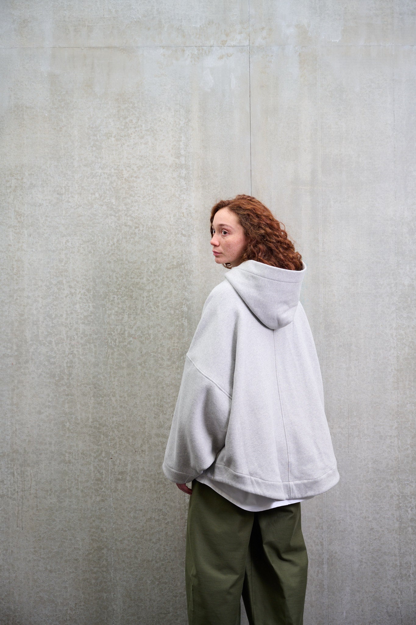 Sweat à capuche oversize en molleton de coton gris chiné Mino de la marque Aïdama. Porté par une mannequin femme et vu de dos.