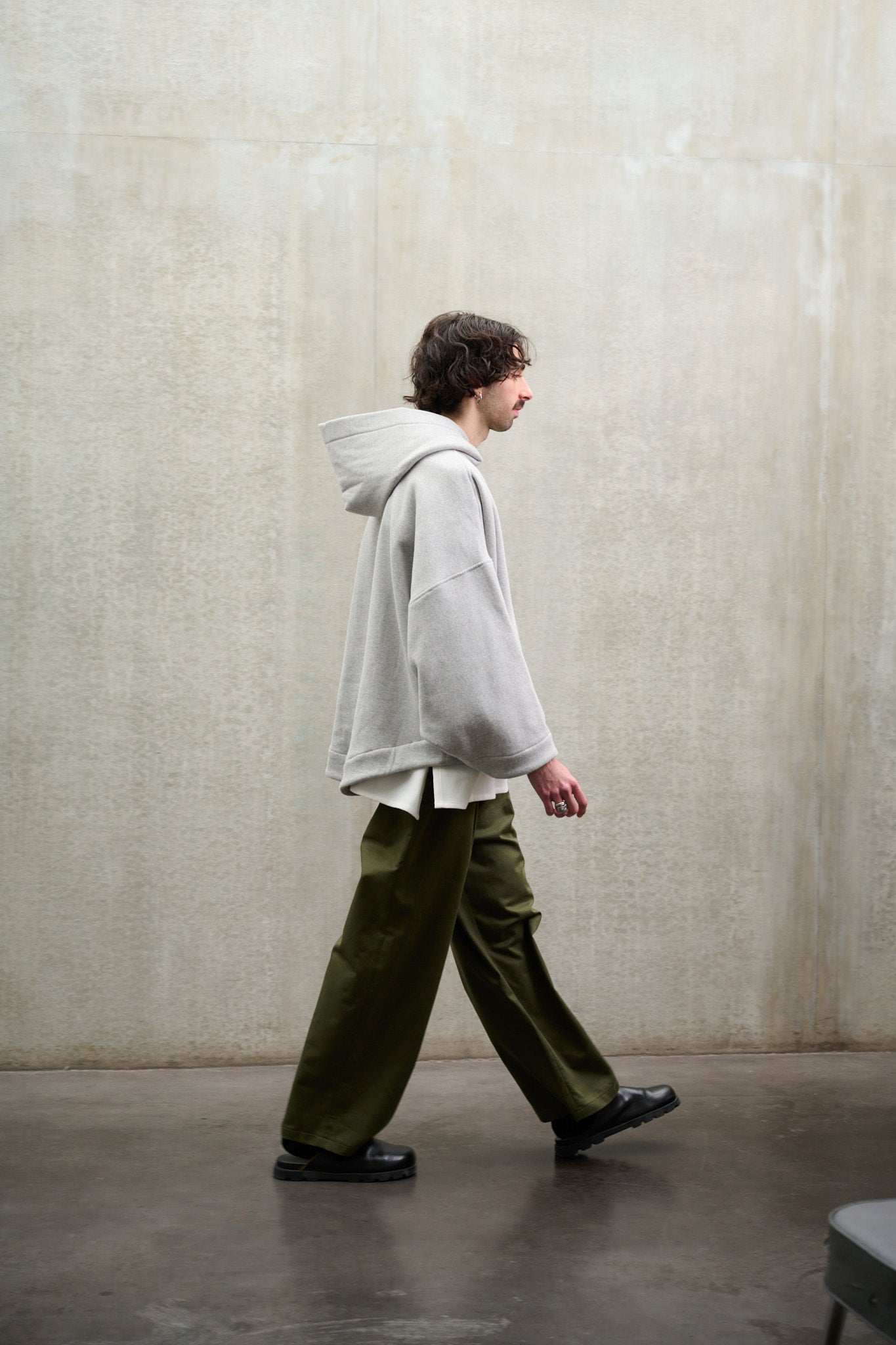 Sweat à capuche oversize en molleton de coton gris chiné Mino de la marque Aïdama. Porté par un mannequin homme et vu de profil.