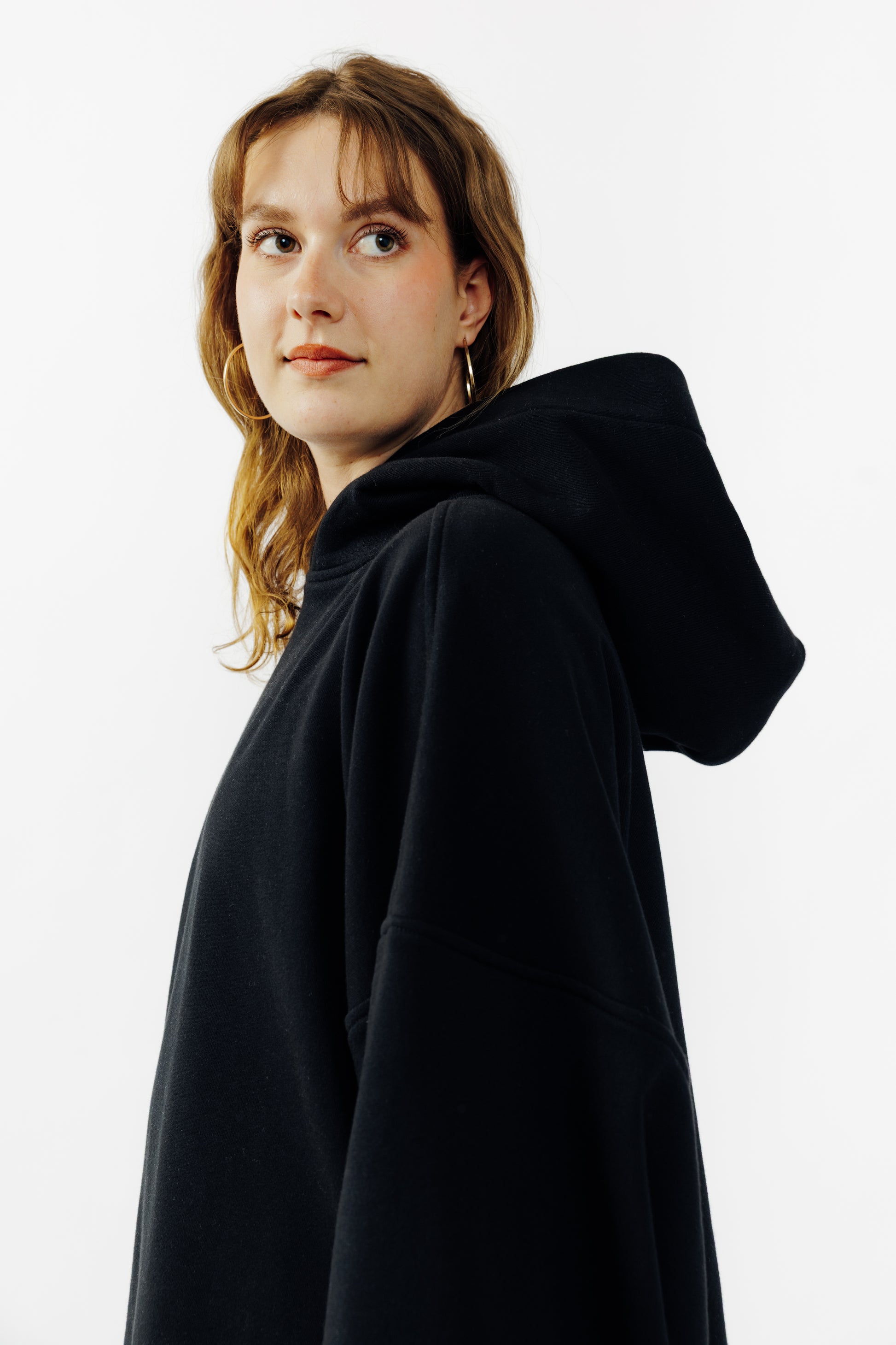 Sweat à capuche oversize Mino de la marque Aïdama en molleton de coton noir. Porté par une mannequin femme et vu de profil. 