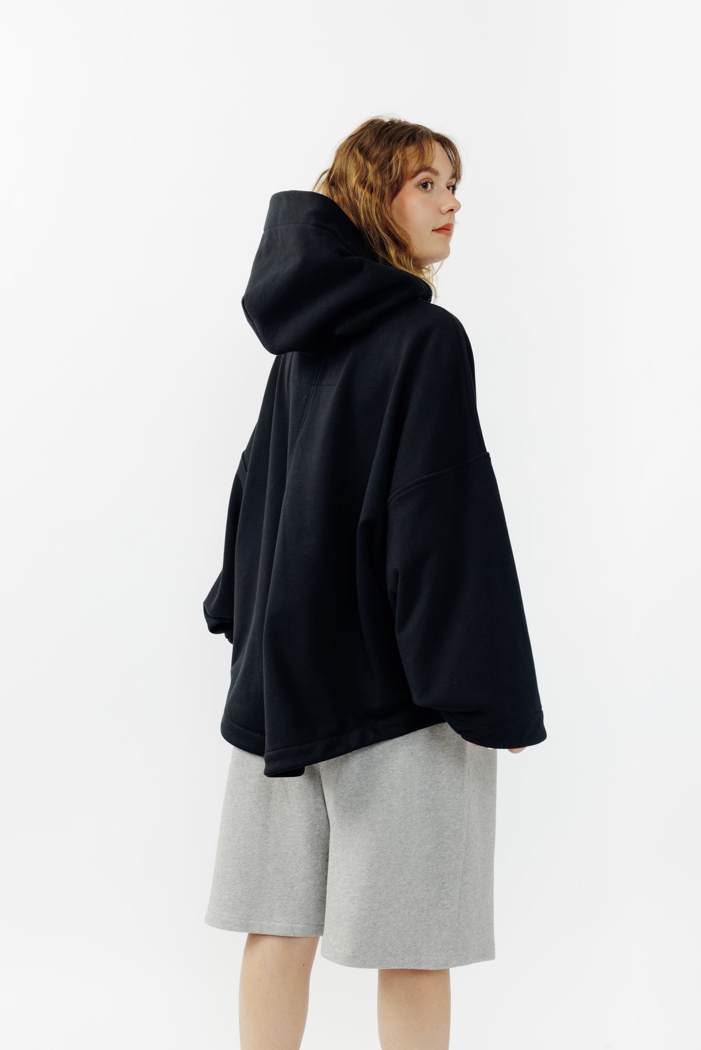 Sweat à capuche oversize Mino de la marque Aïdama en molleton de coton noir. Porté par une mannequin femme et vu de dos.