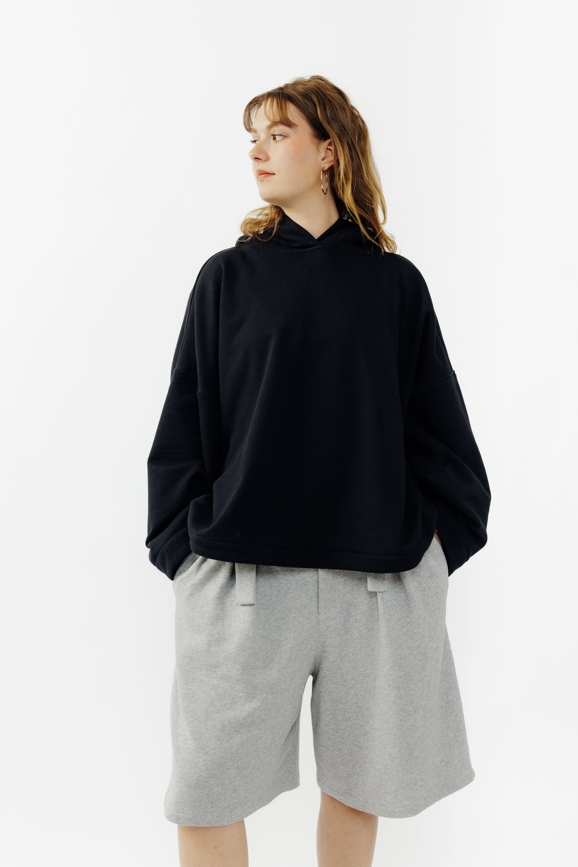 Sweat à capuche oversize Mino de la marque Aïdama en molleton de coton noir. Porté par une mannequin femme et vu de face.