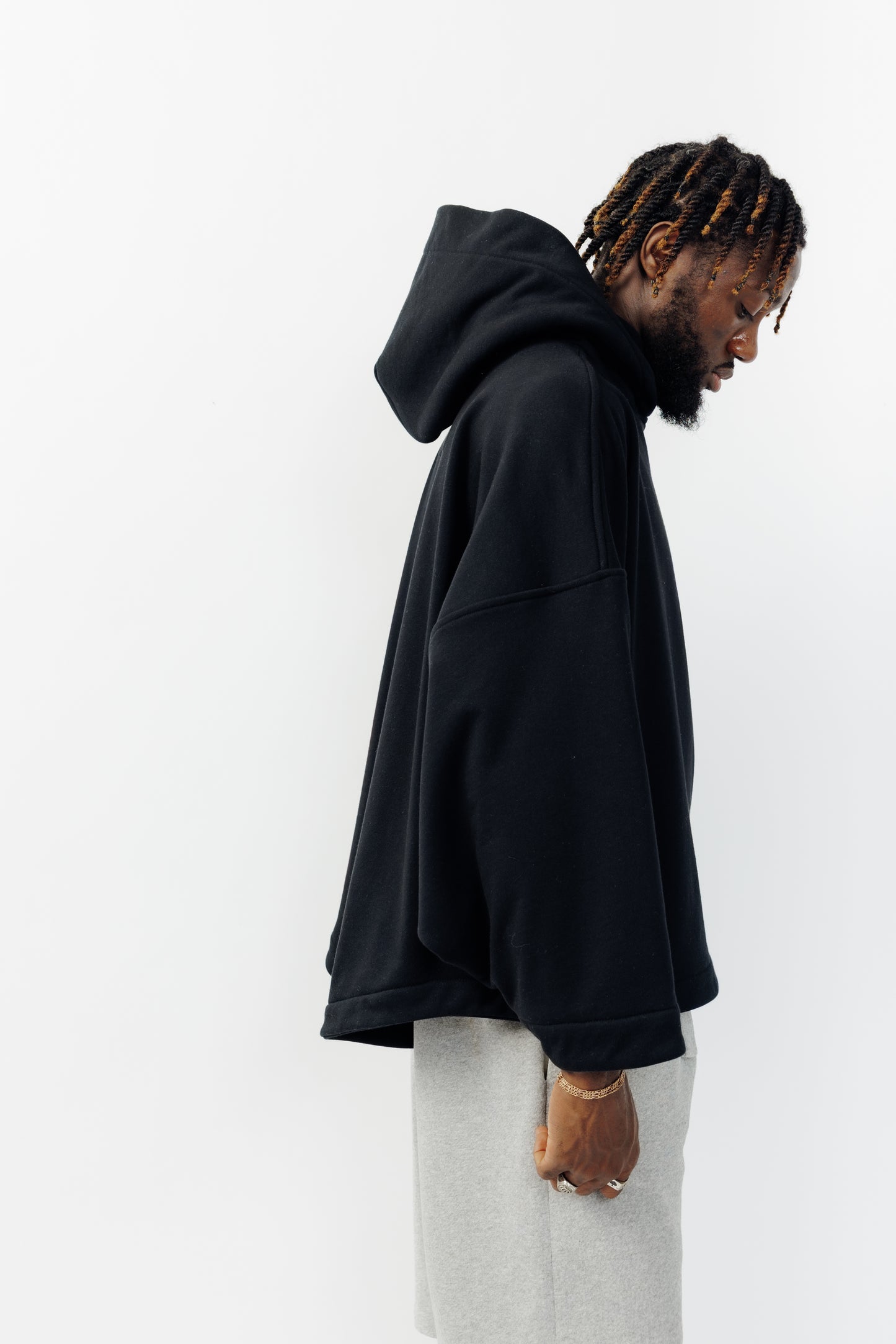 Sweat à capuche oversize Mino de la marque Aïdama en molleton de coton noir. Porté par un mannequin homme et vu de profil. 