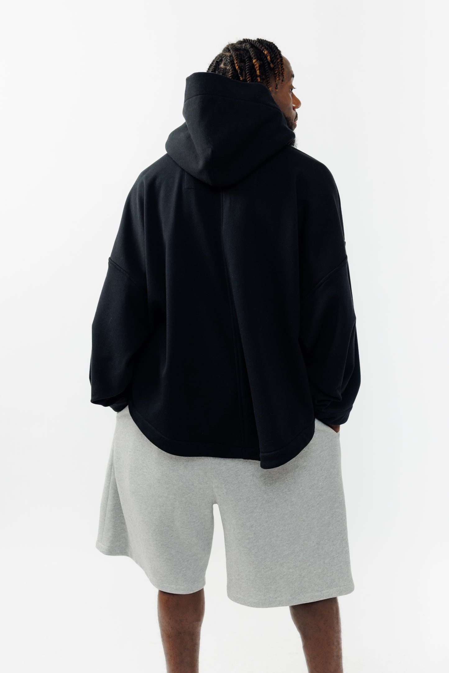 Sweat à capuche oversize Mino de la marque Aïdama en molleton de coton noir. Porté par un mannequin homme et vu de dos. 