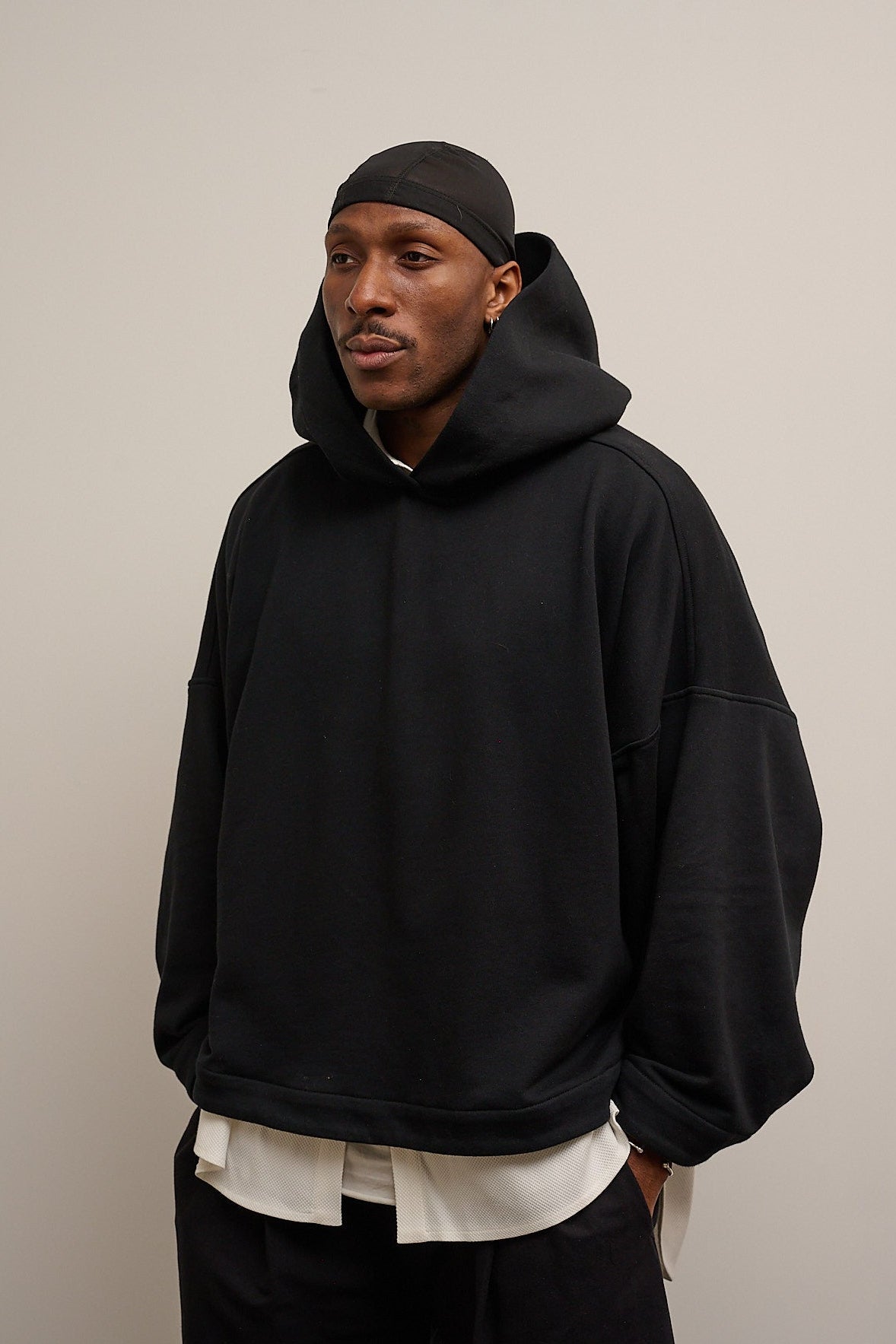 Sweat à capuche oversize en molleton de coton noir Mino de la marque Aïdama. Porté par un mannequin homme et vu de face.
