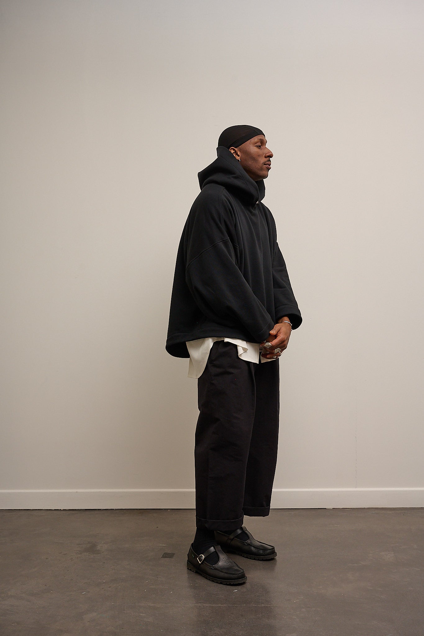 Sweat à capuche oversize Mino de la marque Aïdama en molleton de coton noir. Porté par un mannequin homme et vu de profil