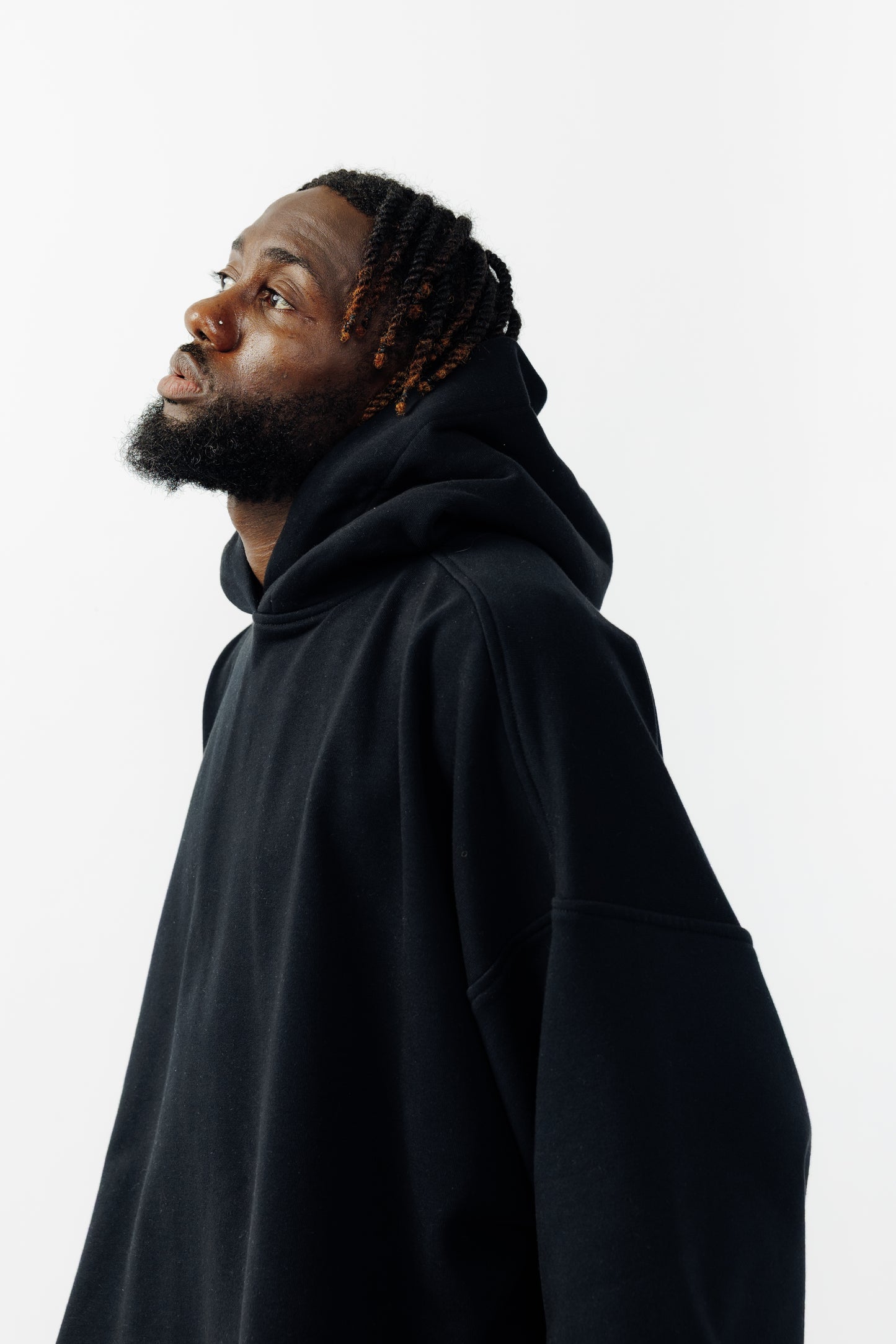 Sweat à capuche oversize Mino de la marque Aïdama en molleton de coton noir. Porté par un mannequin homme et vu de profil. 
