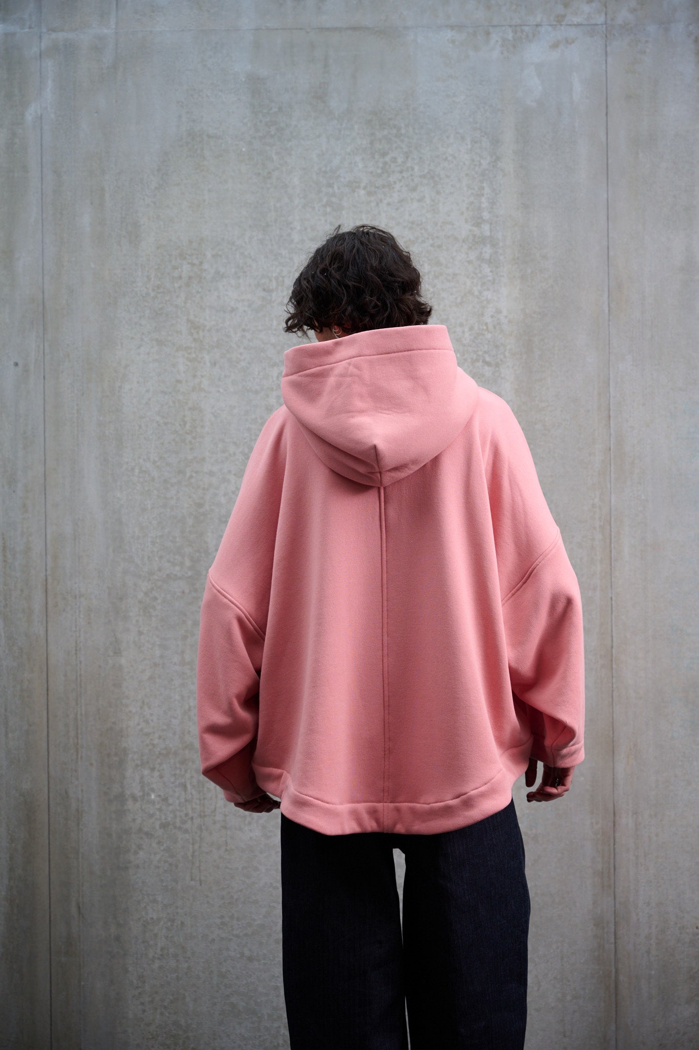 Sweat à capuche oversize en molleton de coton rose pâle Mino de la marque Aïdama. Porté par un mannequin homme et vu de dos.
