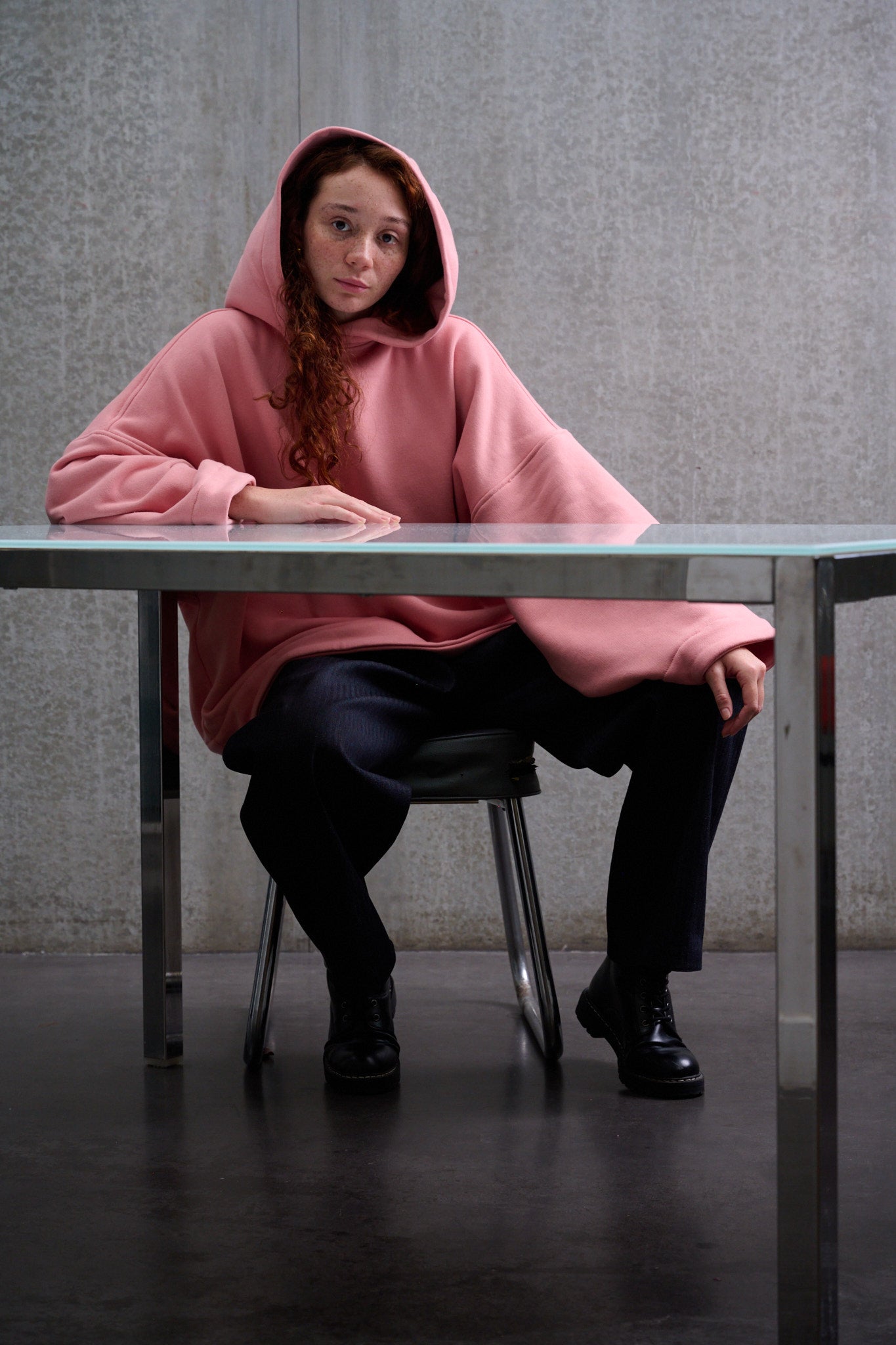 Sweat à capuche oversize en molleton de coton rose pâle Mino de la marque Aïdama. Porté par une mannequin femme et vu de face assise à tâble.