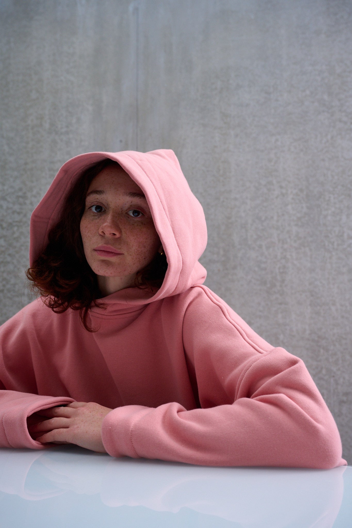 Sweat à capuche oversize en molleton de coton rose pâle Mino de la marque Aïdama. Porté capuché par une mannequin femme et vu de face.