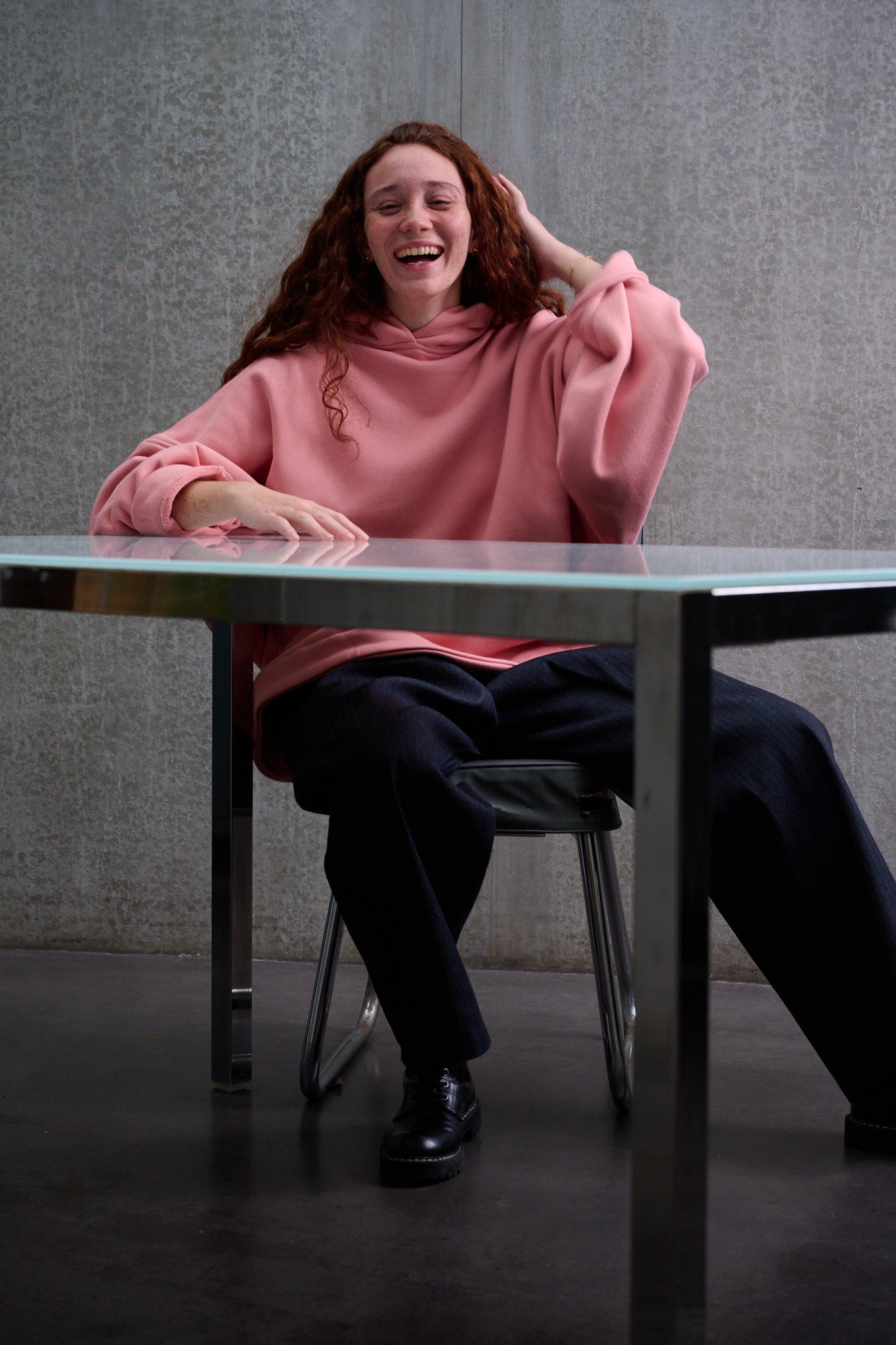 Sweat à capuche oversize en molleton de coton rose pâle Mino de la marque Aïdama. Porté par une mannequin femme et vu de face, assise à table.