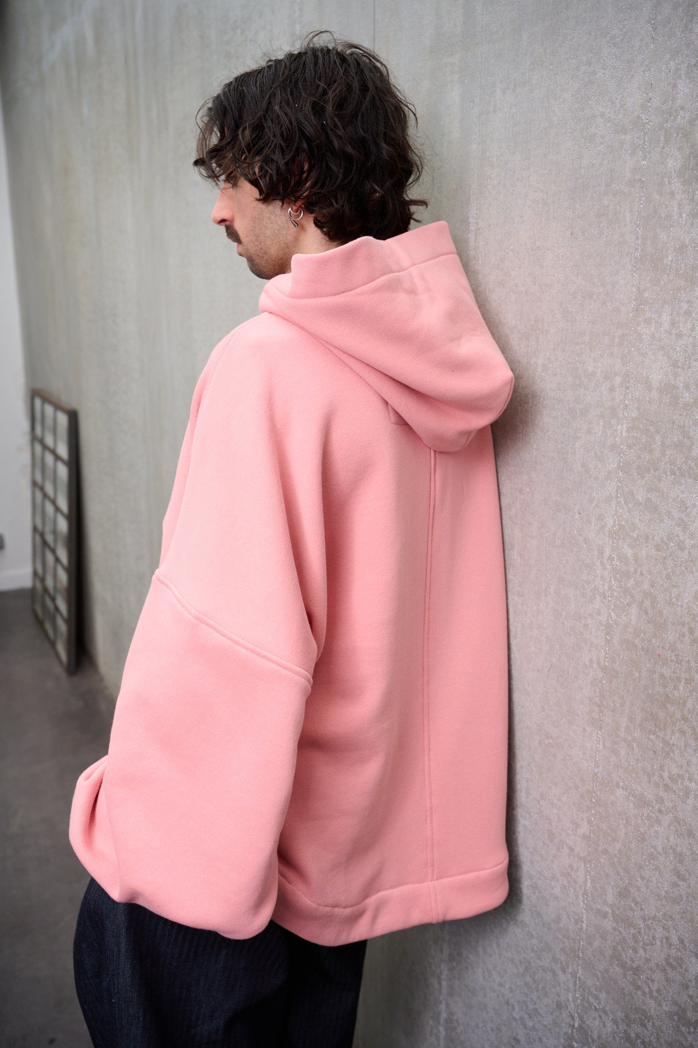 Sweat à capuche oversize en molleton de coton rose pâle Mino de la marque Aïdama. Porté par un mannequin homme et vu de dos.