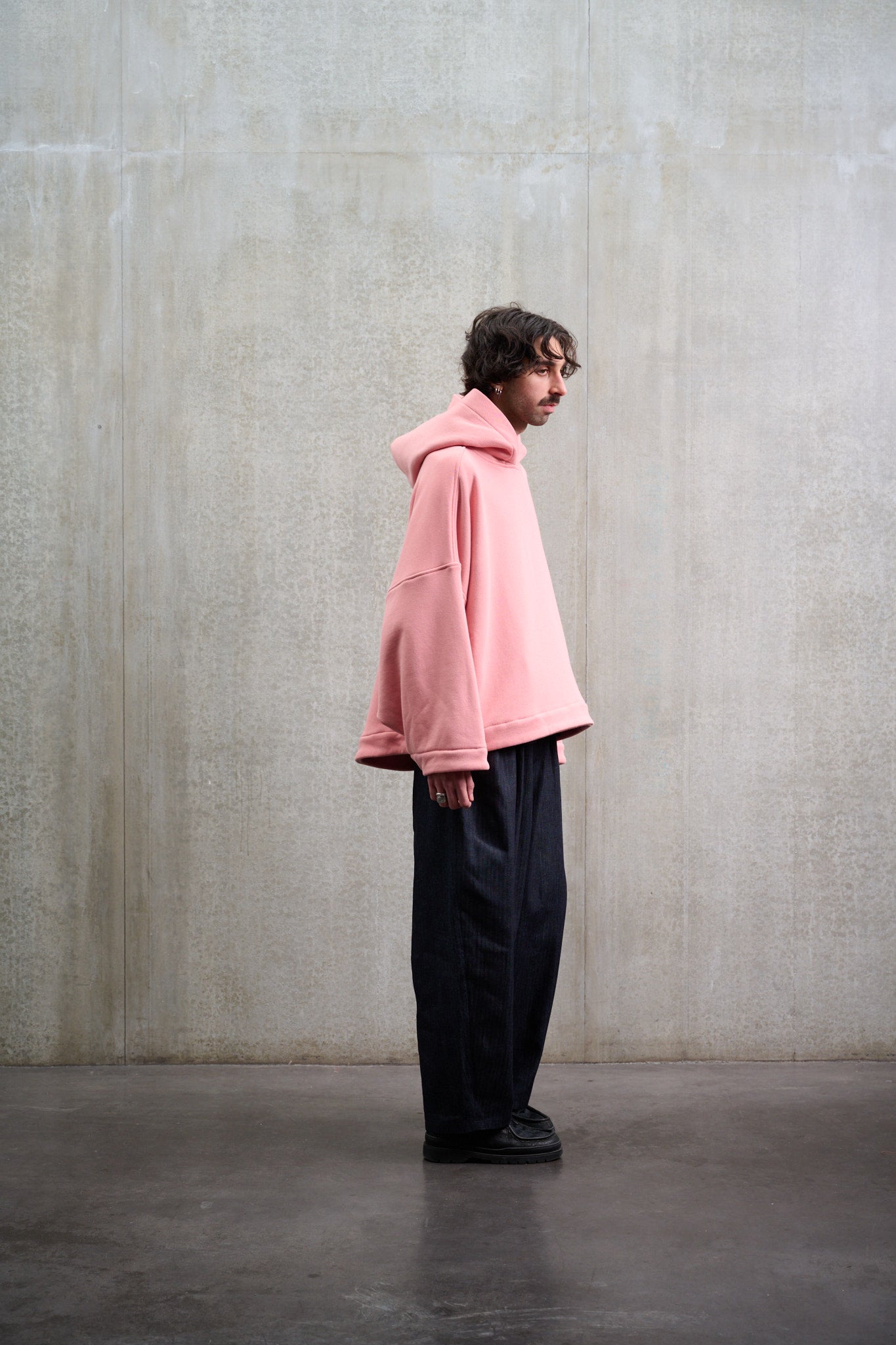 Sweat à capuche oversize en molleton de coton rose pâle Mino de la marque Aïdama. Porté par un mannequin homme et vu de profil.
