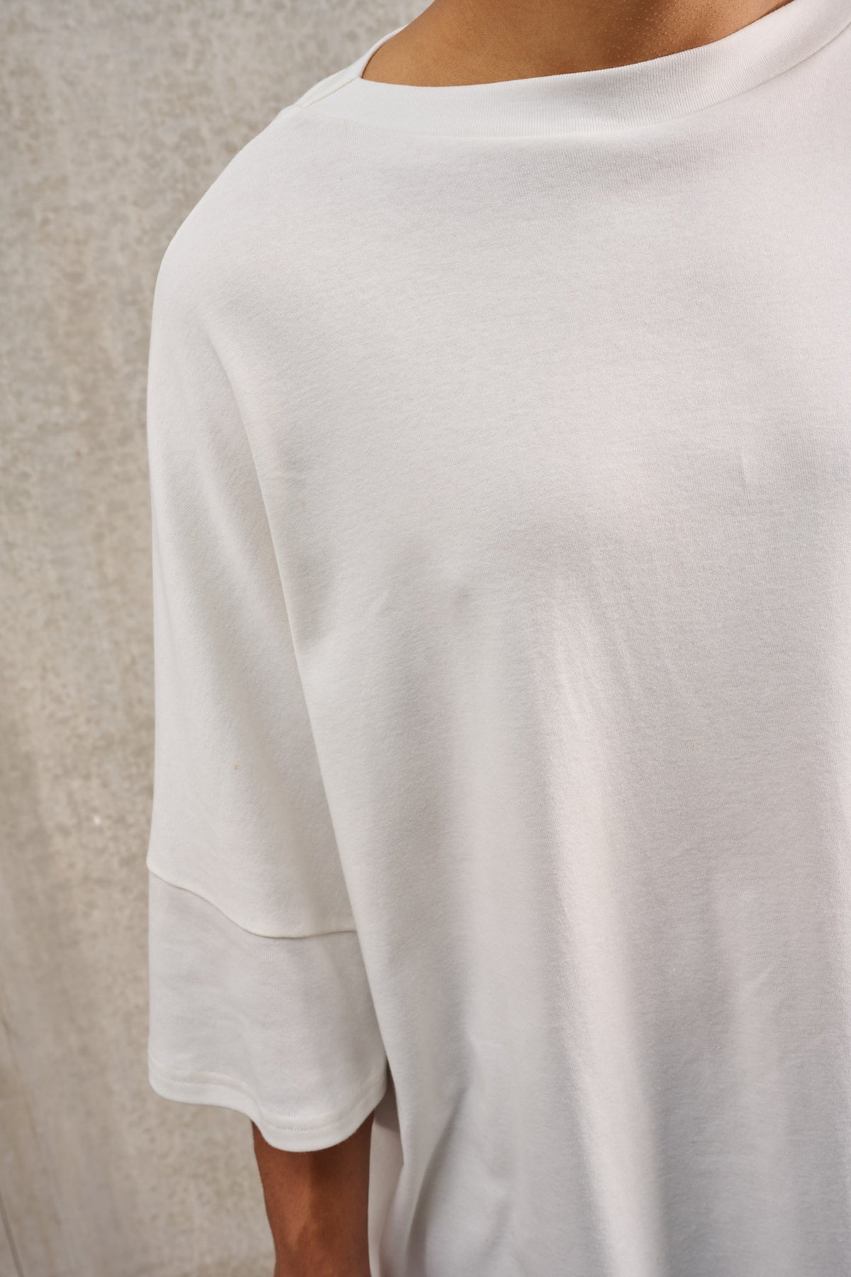 T-shirt oversize à col bateau de la marque Aïdama, modèle Haku en jersey de coton blanc certifié GOTS. Porté par un mannequin homme et vu zoomé sur le col.