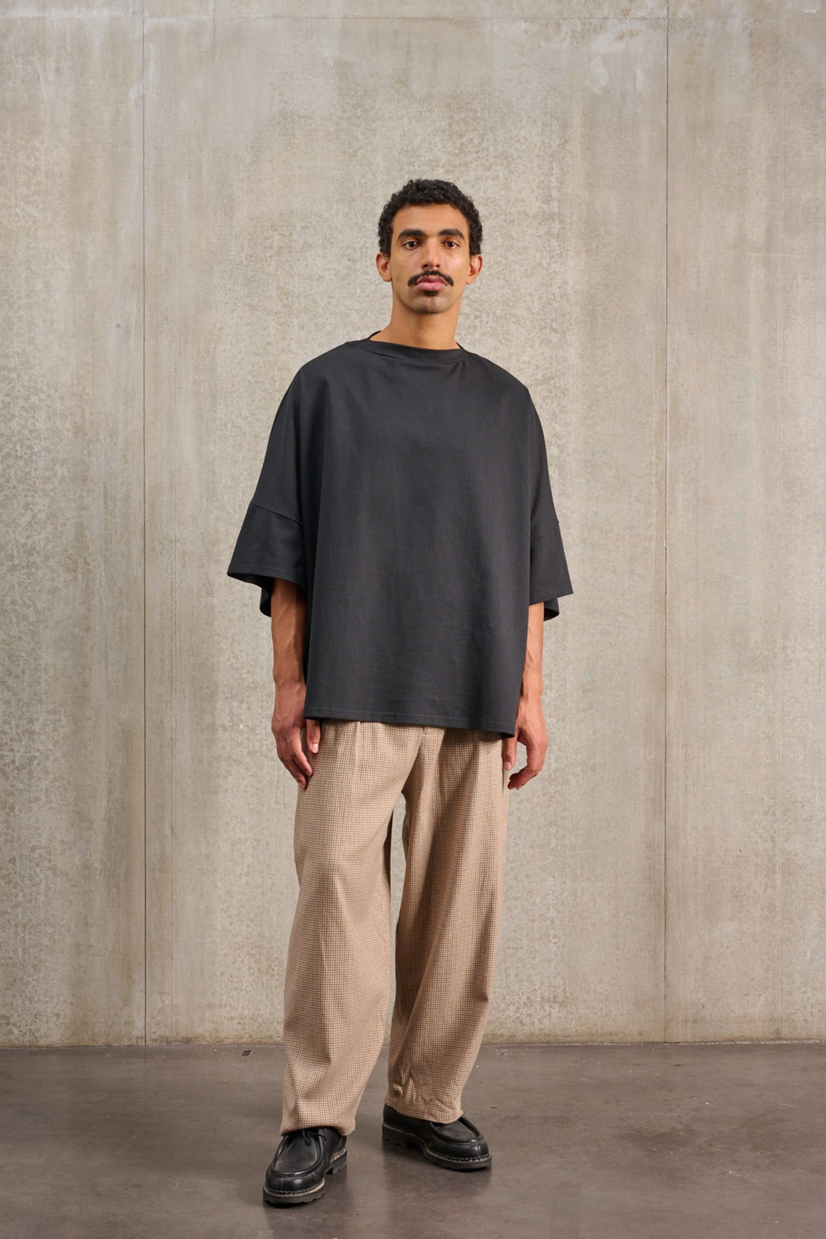 T-shirt oversize à col bateau de la marque Aïdama, modèle Haku en jersey de coton noir épais. Porté par un mannequin homme et vu de face.