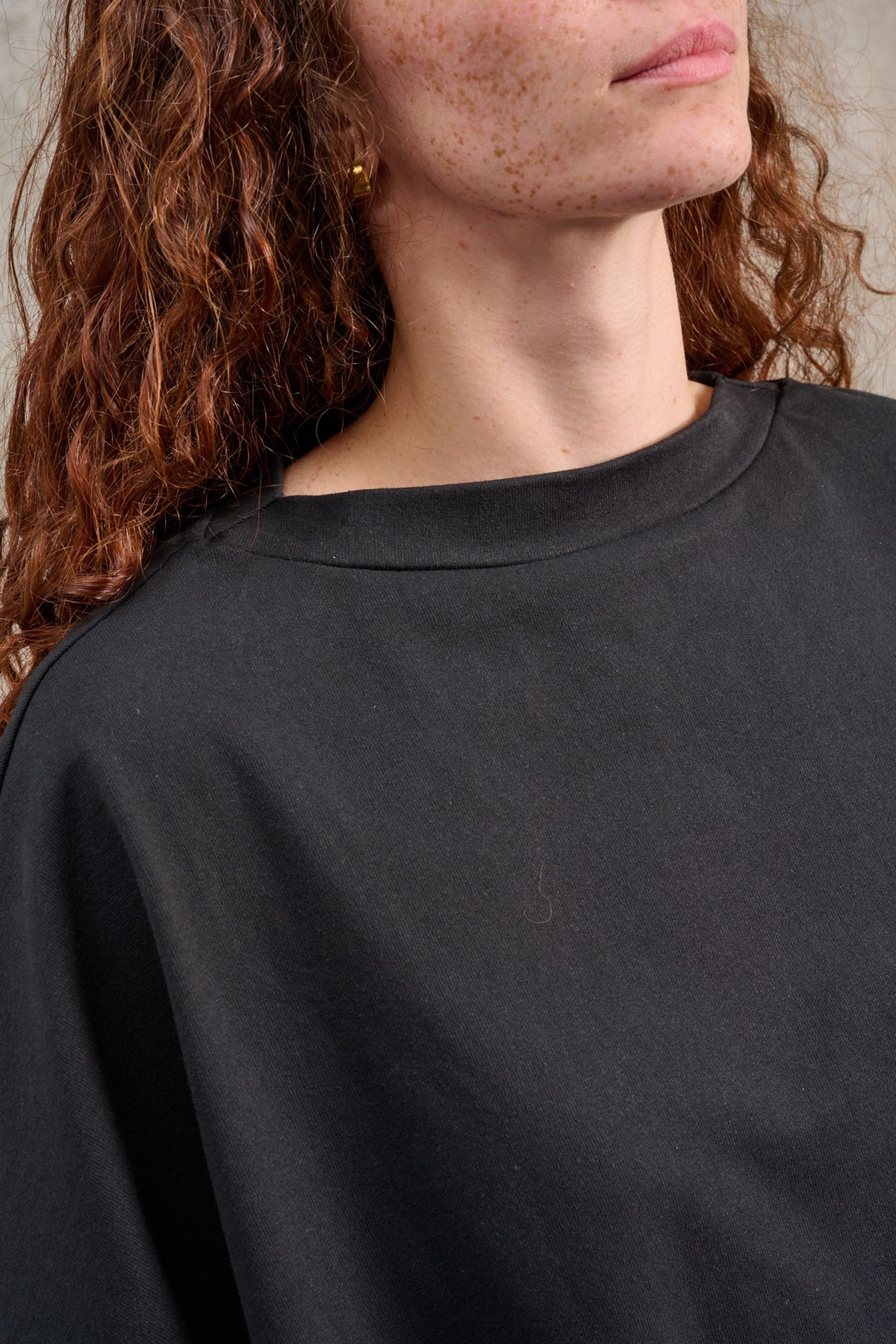 T-shirt oversize à col bateau de la marque Aïdama, modèle Haku en jersey de coton noir épais. Porté par une mannequin femme et vu zoomé sur le col.