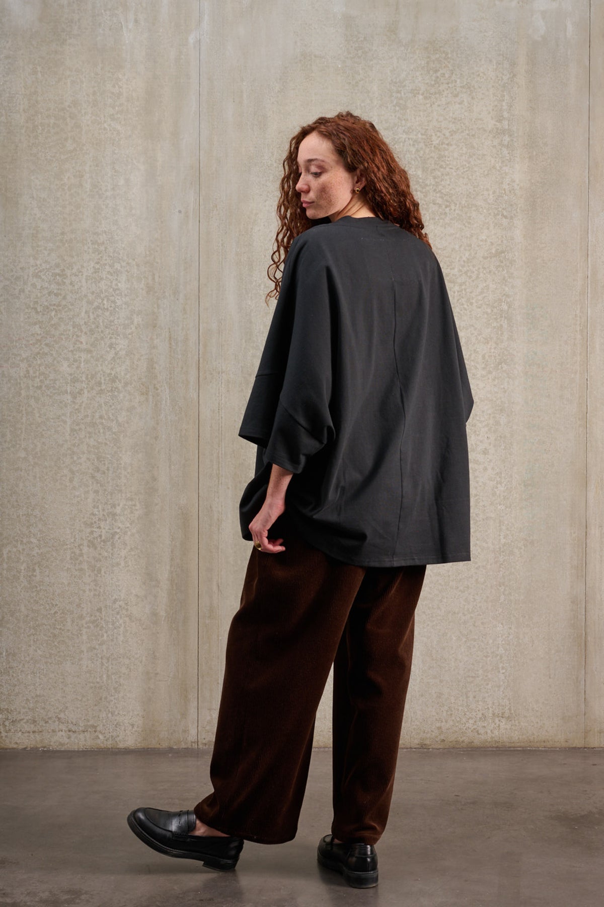 T-shirt oversize à col bateau de la marque Aïdama, modèle Haku en jersey de coton noir épais. Porté par une mannequin femme et vu de dos.