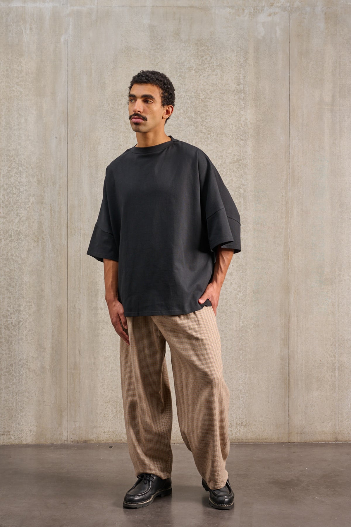 T-shirt oversize à col bateau de la marque Aïdama, modèle Haku en jersey de coton noir épais. Porté par un mannequin homme et vu de face.