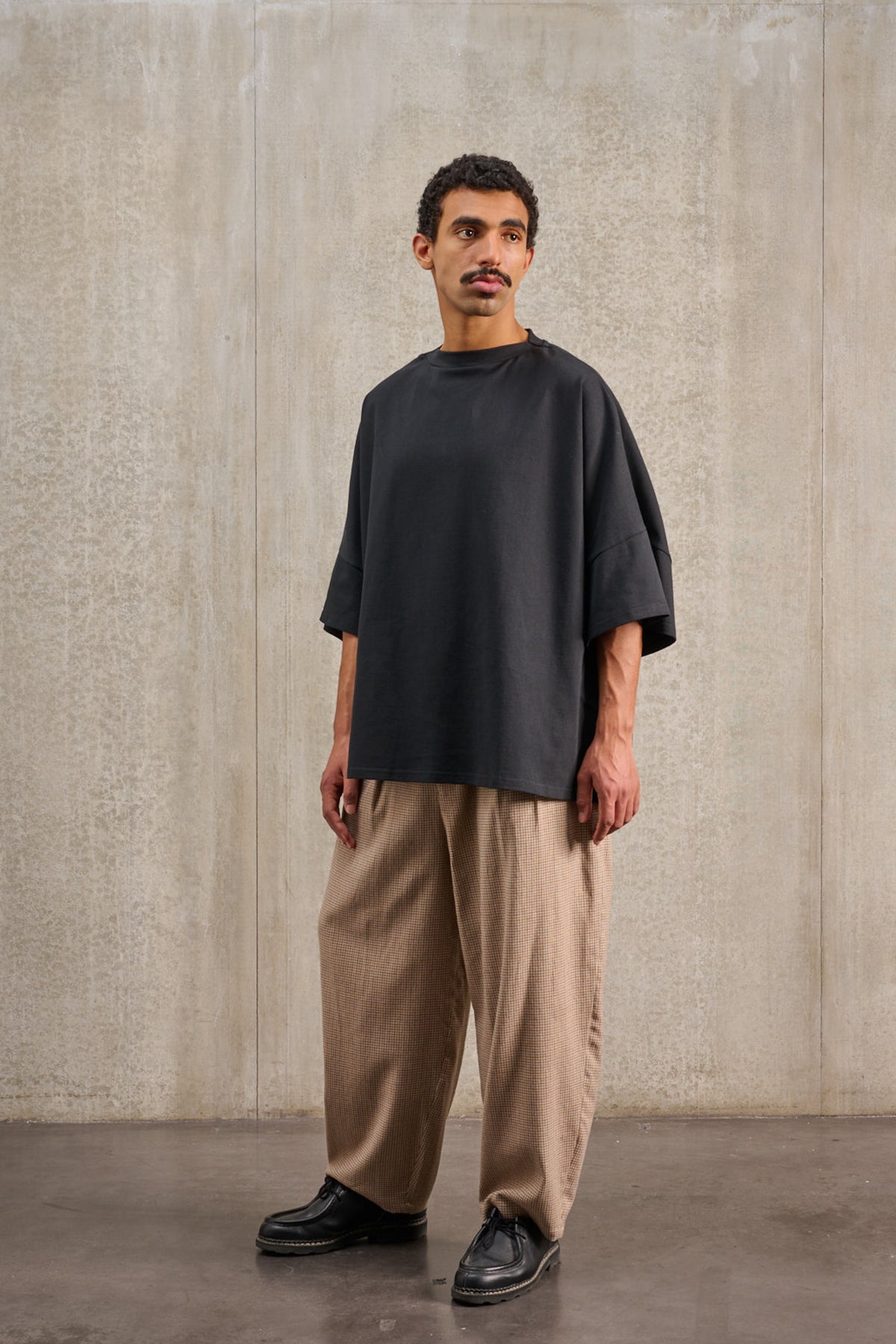 T-shirt oversize à col bateau de la marque Aïdama, modèle Haku en jersey de coton noir épais. Porté par un mannequin homme et vu de trois quarts.