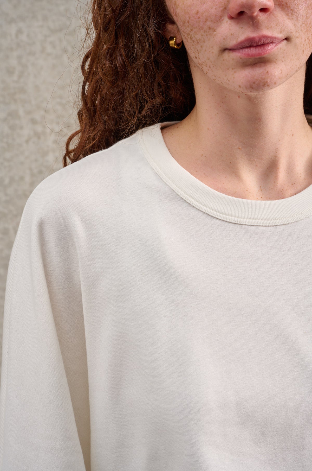 T-shirt oversize à col rond de la marque Aïdama, modèle Haku en jersey de coton blanc GOTS. Porté par une mannequin femme et vu zoomé sur le col.