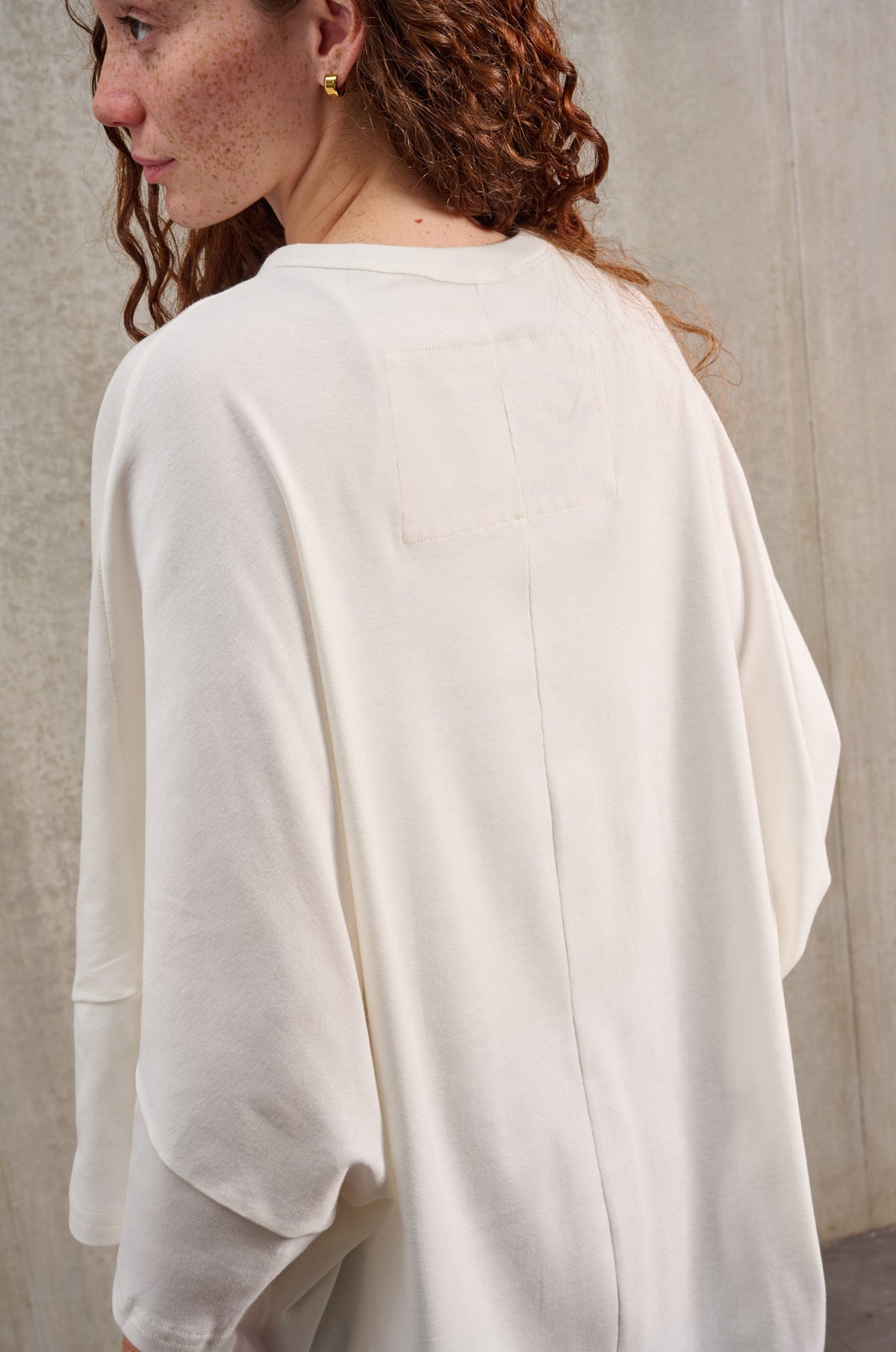 T-shirt oversize à col rond de la marque Aïdama, modèle Haku en jersey de coton blanc GOTS. Porté par une mannequin femme et vue de dos.