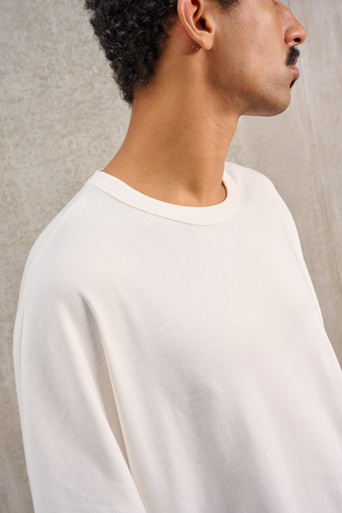 T-shirt oversize à col rond de la marque Aïdama, modèle Haku en jersey de coton blanc GOTS. Porté par un mannequin homme et vu zoomé sur le col.