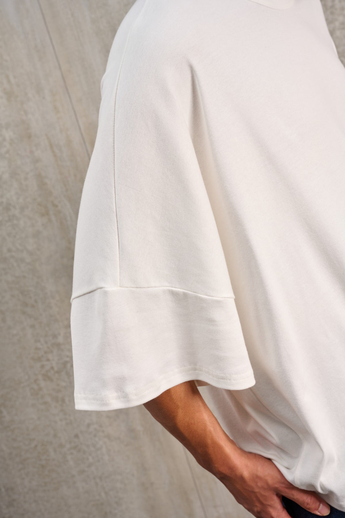 T-shirt oversize à col rond de la marque Aïdama, modèle Haku en jersey de coton blanc GOTS. Porté par un mannequin homme et vu zoomé sur la manche.