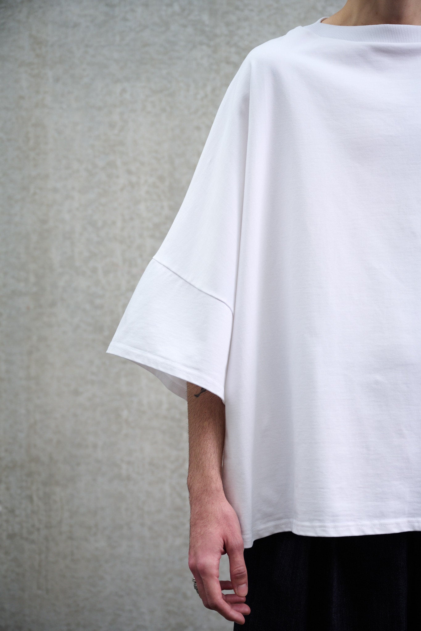 T-shirt oversize à col bateau Haku en coton épais blanc de la marque Aïdama. Porté par un mannequin homme et vu zoomé sur la manche.