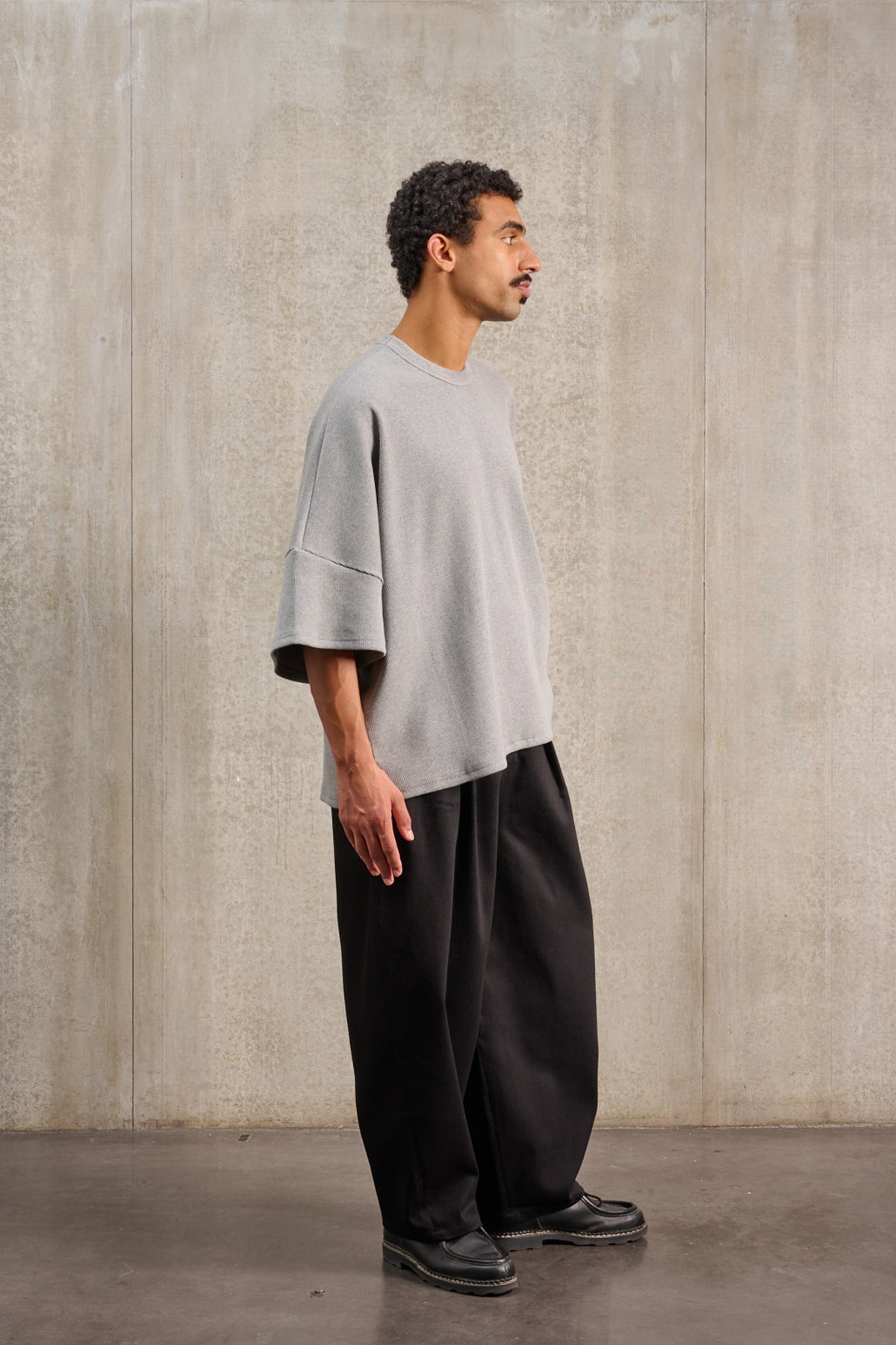 T-shirt oversize à col rond de la marque Aïdama, modèle Haku en jersey côtelé de coton gris chiné. Porté par un mannequin homme et vu de profil.