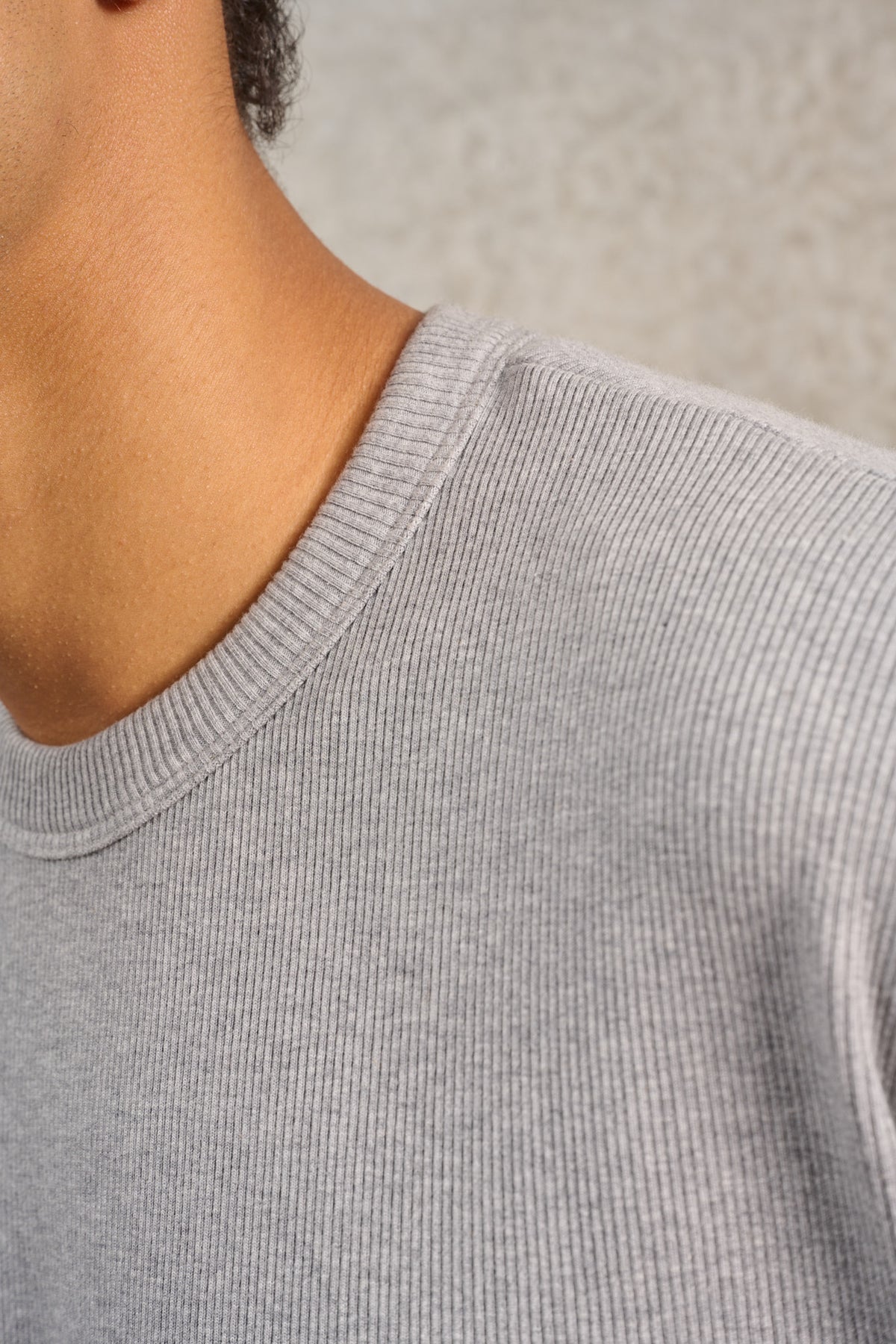 T-shirt oversize à col rond de la marque Aïdama, modèle Haku en jersey côtelé de coton gris chiné. Porté par un mannequin homme et vu de face zoomé sur le col.