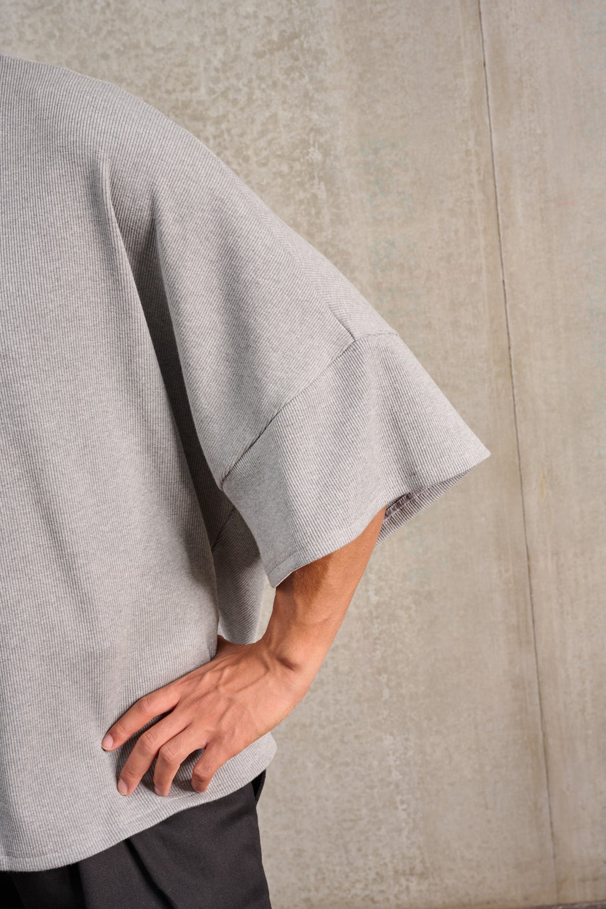 T-shirt oversize à col rond de la marque Aïdama, modèle Haku en jersey côtelé de coton gris chiné. Porté par un mannequin homme et vu de face zoomé sur la manche.