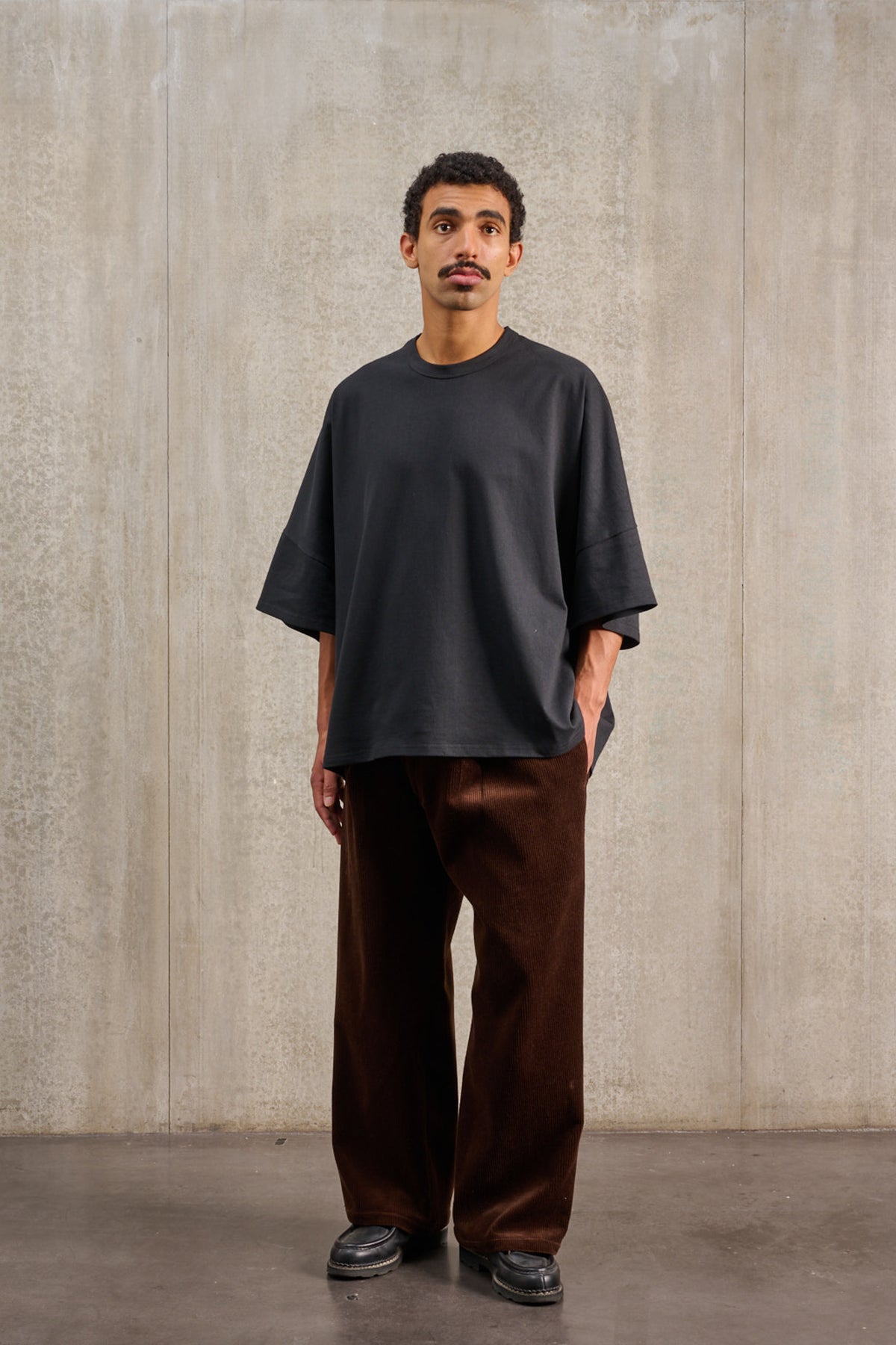 T-shirt oversize à col rond de la marque Aïdama, modèle Haku en jersey de coton noir. Porté par un mannequin homme et vu de face.