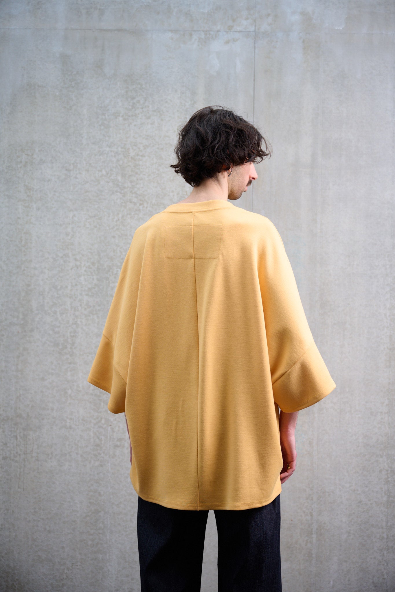 T-shirt oversize à col bateau Haku en laine jaune de la marque Aïdama. Porté par un mannequin homme et vu de dos.