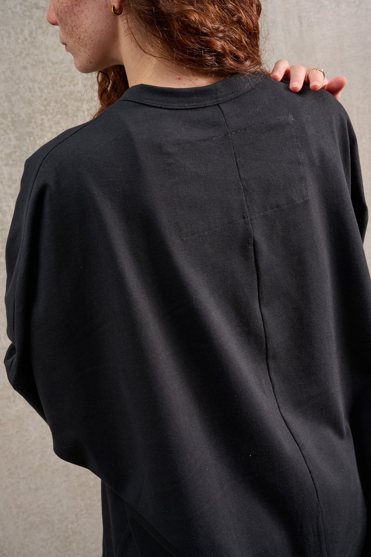 T-shirt oversize à col rond de la marque Aïdama, modèle Haku en jersey de coton noir. Porté par une mannequin femme et vu de dos.