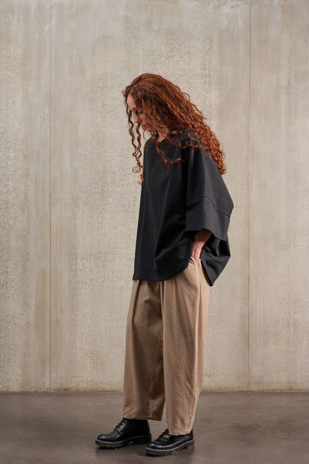 T-shirt oversize à col rond de la marque Aïdama, modèle Haku en jersey de coton noir. Porté par une mannequin femme et vu de profil.